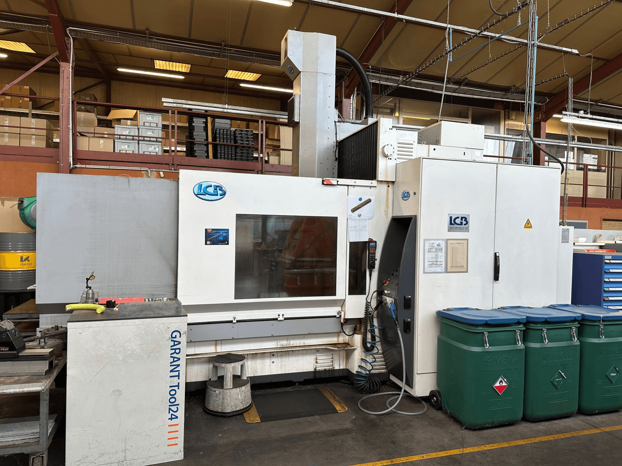 GARANT Tool24 iş istasyonu ve yan tarafta yeşil atık kutuları ile önden görüntülenen LGB CNC makinesi.