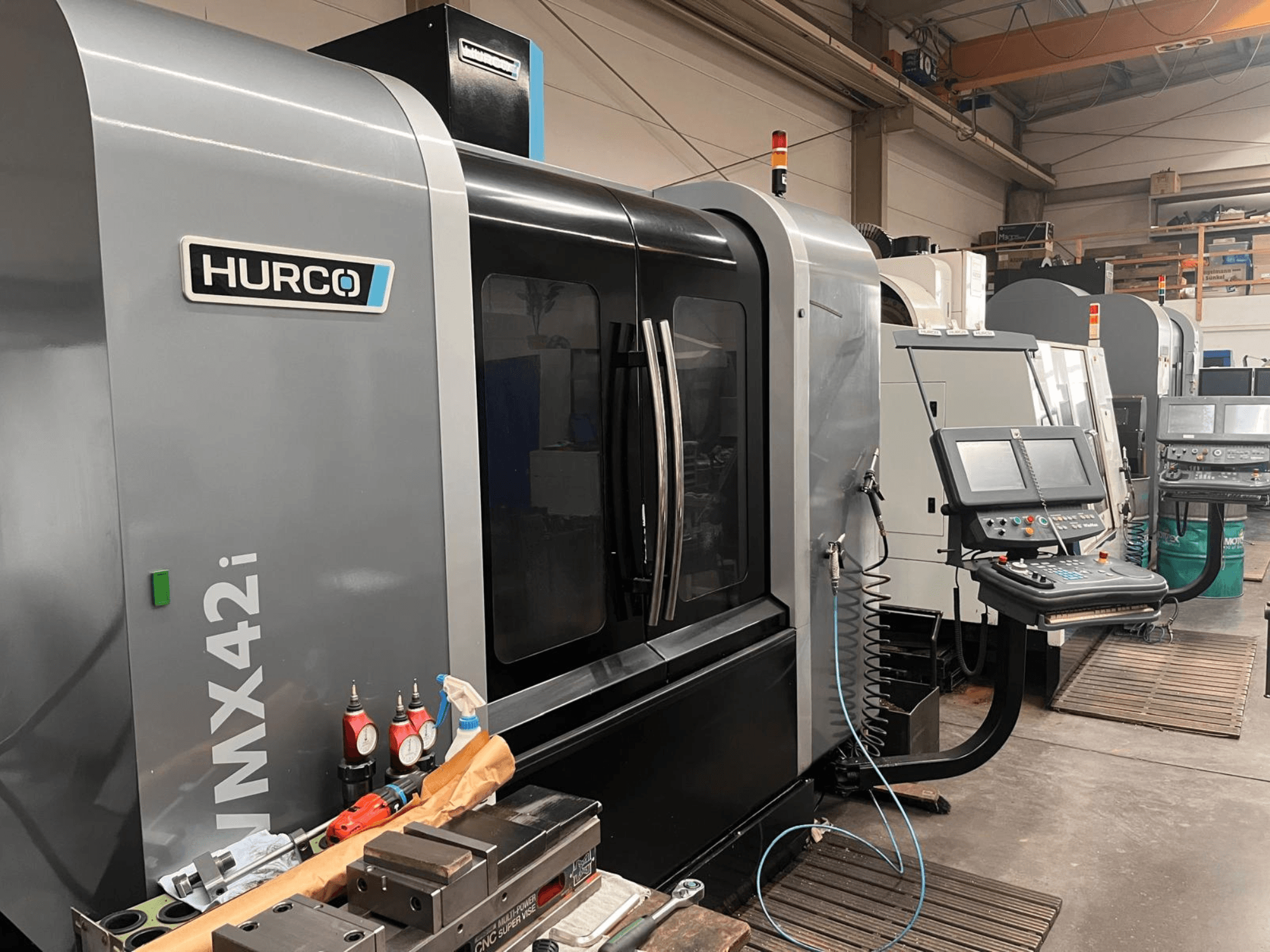 Bir atölyede Hurco VMX42i CNC makinesi, önden görünüm, kontrol paneli ve tezgah üzerindeki çeşitli aletler.