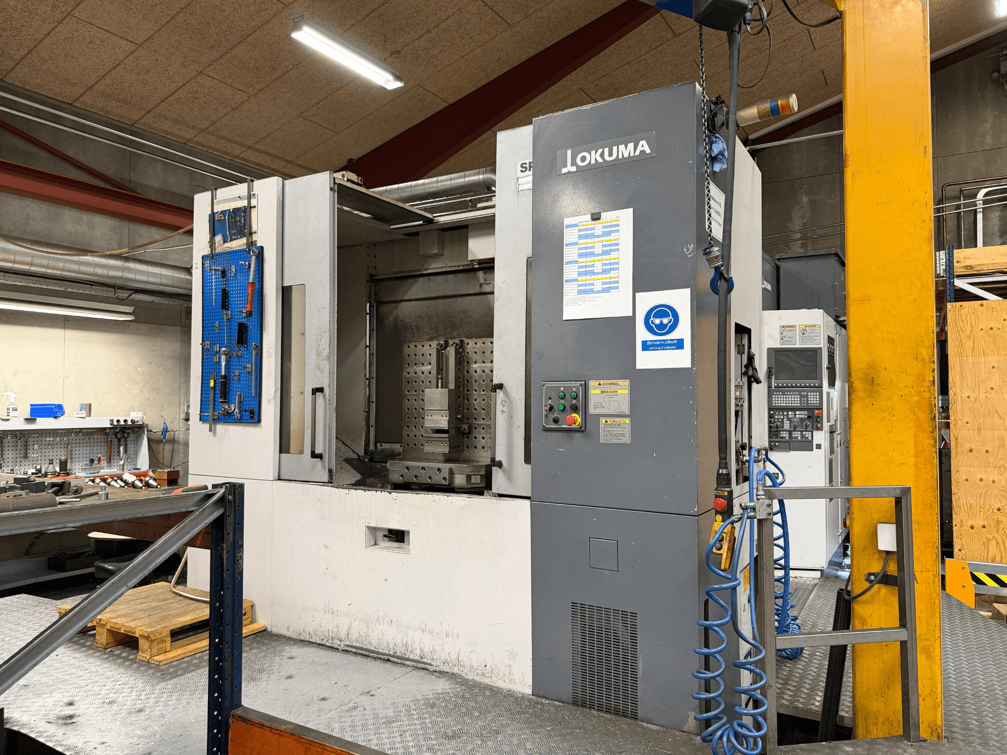 Bir atölyede bulunan Okuma MA-600HB yatay işleme merkezi; kontrol paneli ve çalışma alanını gösteren önden görünüm.