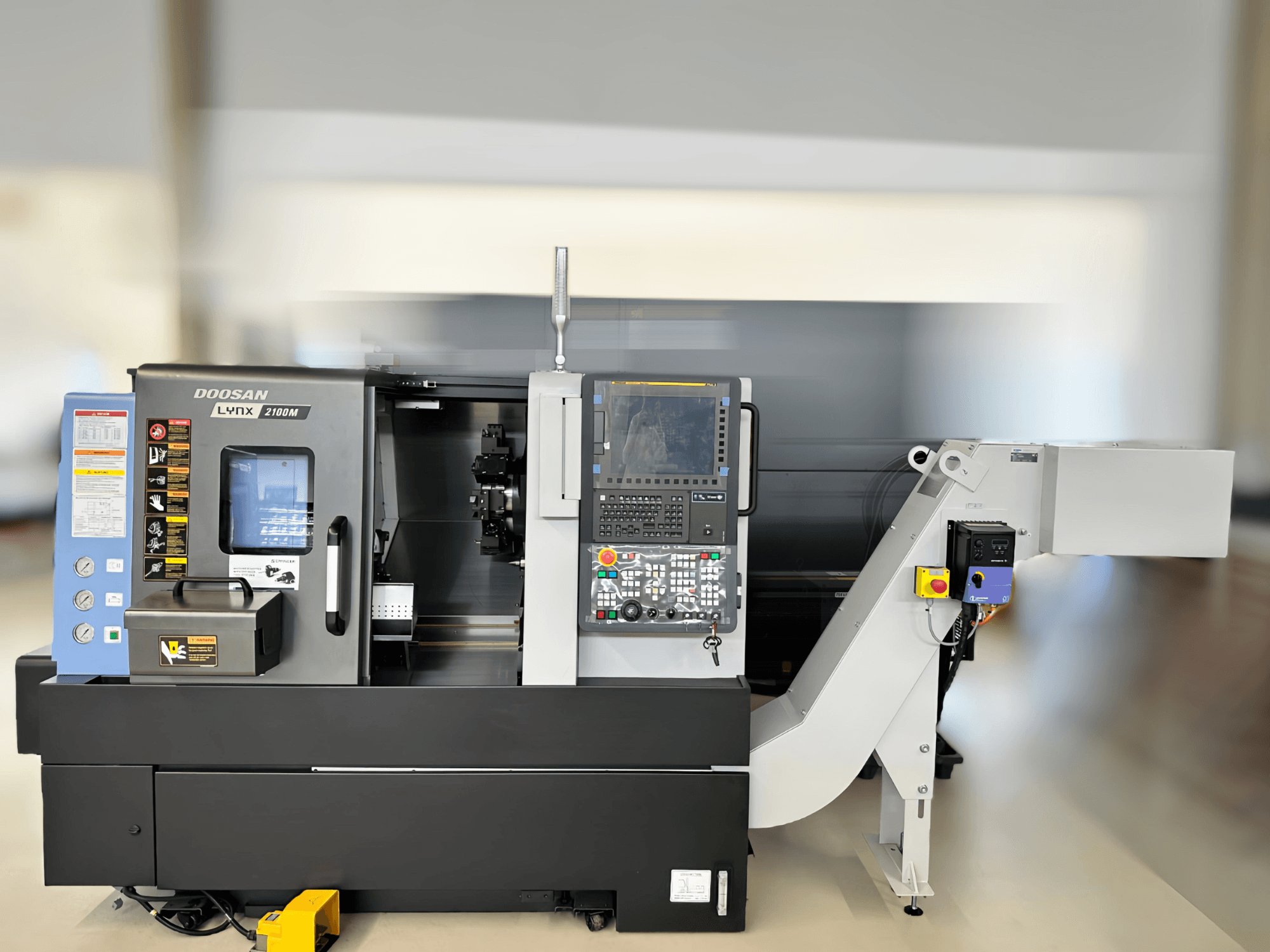DN SOLUTIONS LYNX 2100MB yatay tornalama makinesinin önden görünümü, kontrol paneli ve çalışma alanı detaylarını gösterir.