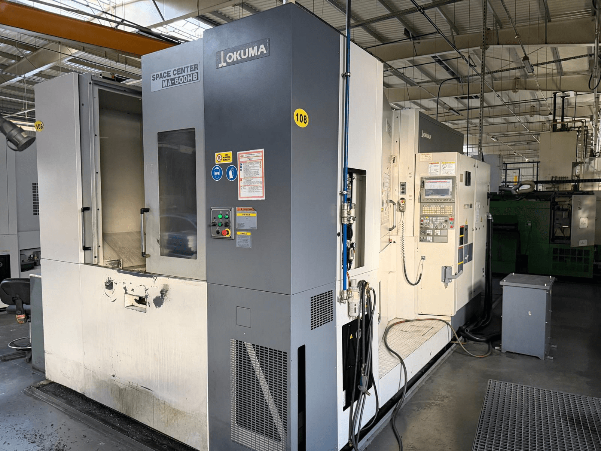 Okuma MA-600 HB yatay işleme merkezi, önden görünüm, kontrol paneli ve görünür aşınma izleri olan kesme alanı.