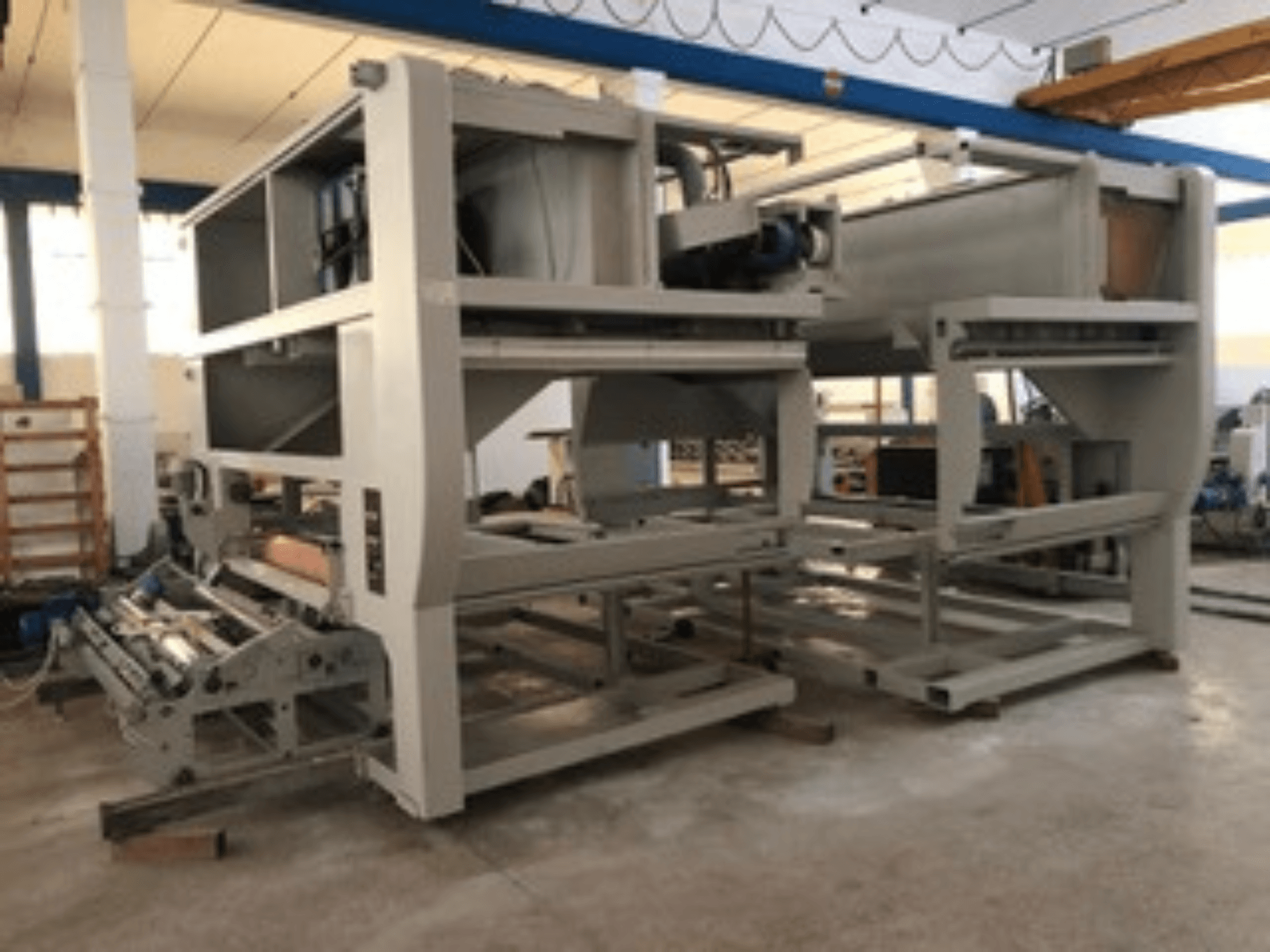 Çoklu konveyör makaralarına ve geniş yapıya sahip endüstriyel makine; yandan görünüm, gri renk, iyi aydınlatılmış bir fabrikada yer almaktadır.