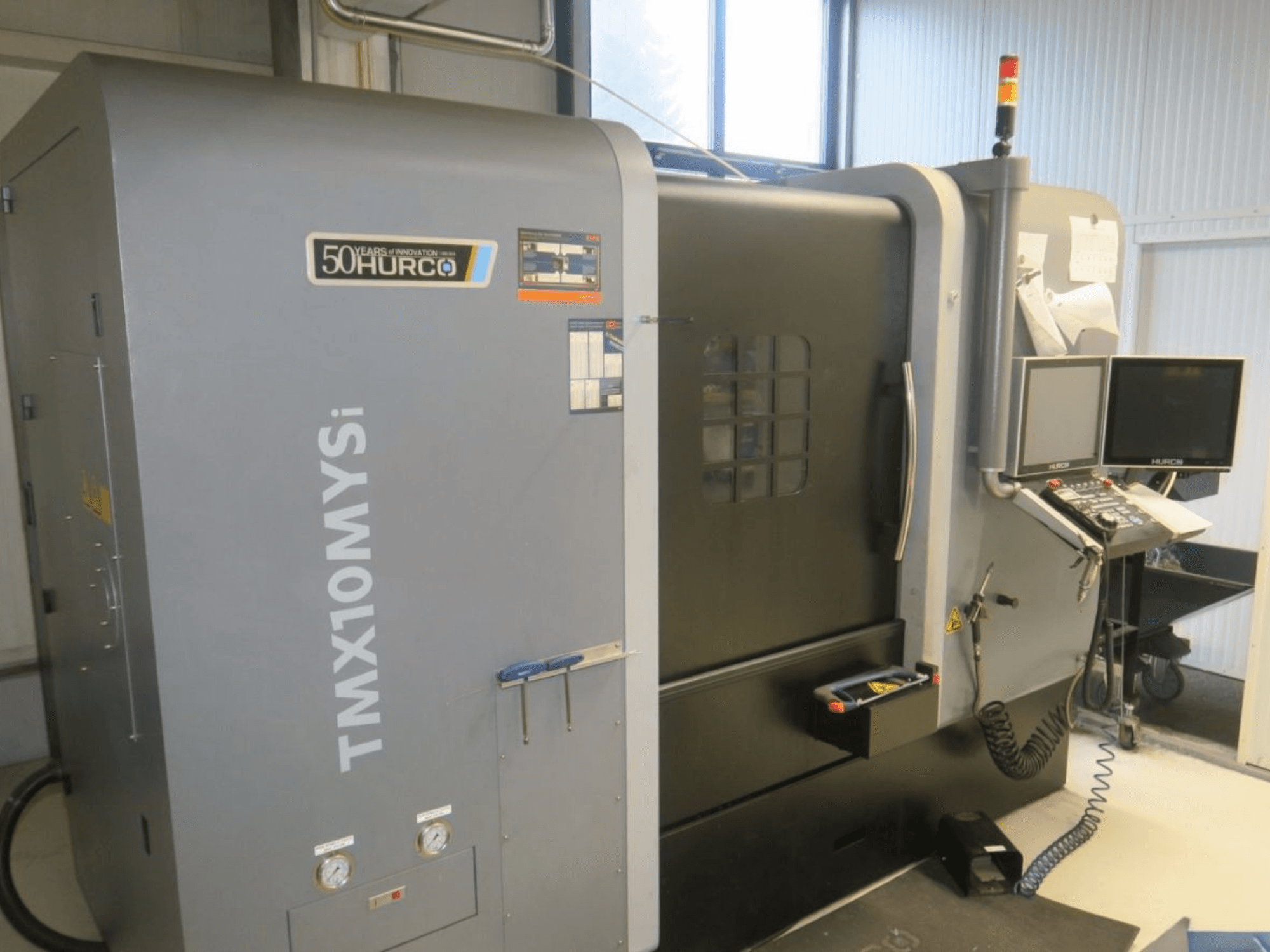 Hurco TMX10MYSi CNC makinesi yandan görünümde; kontrol paneli, acil durum ışıkları ve göstergeler görüntülenir.