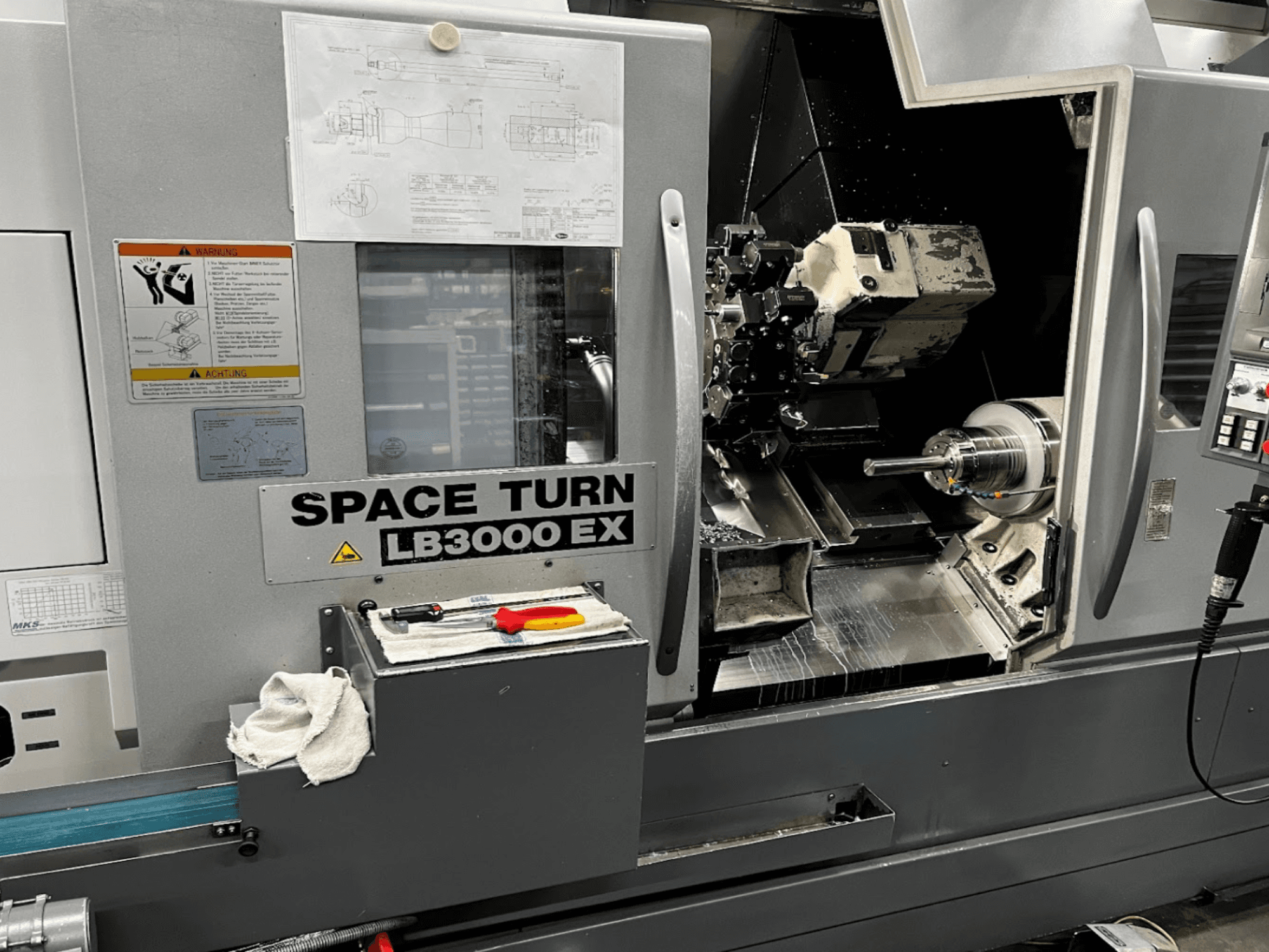 Okuma LB3000EX MYW yatay tornalama makinesi, kontrol paneli, takımlar ve çalışma alanı detaylarının göründüğü önden görünüm.