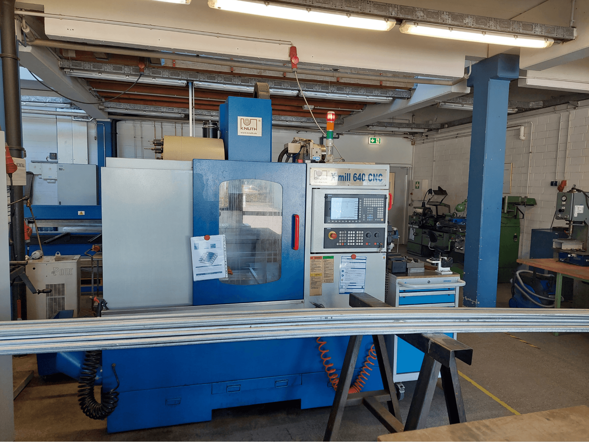 KNUTH X-Mill 640 dikey işleme merkezi, önden görünüm; bir atölye ortamında kontrol paneli ve işleme yüzeyi ile birlikte gösterilmiştir.