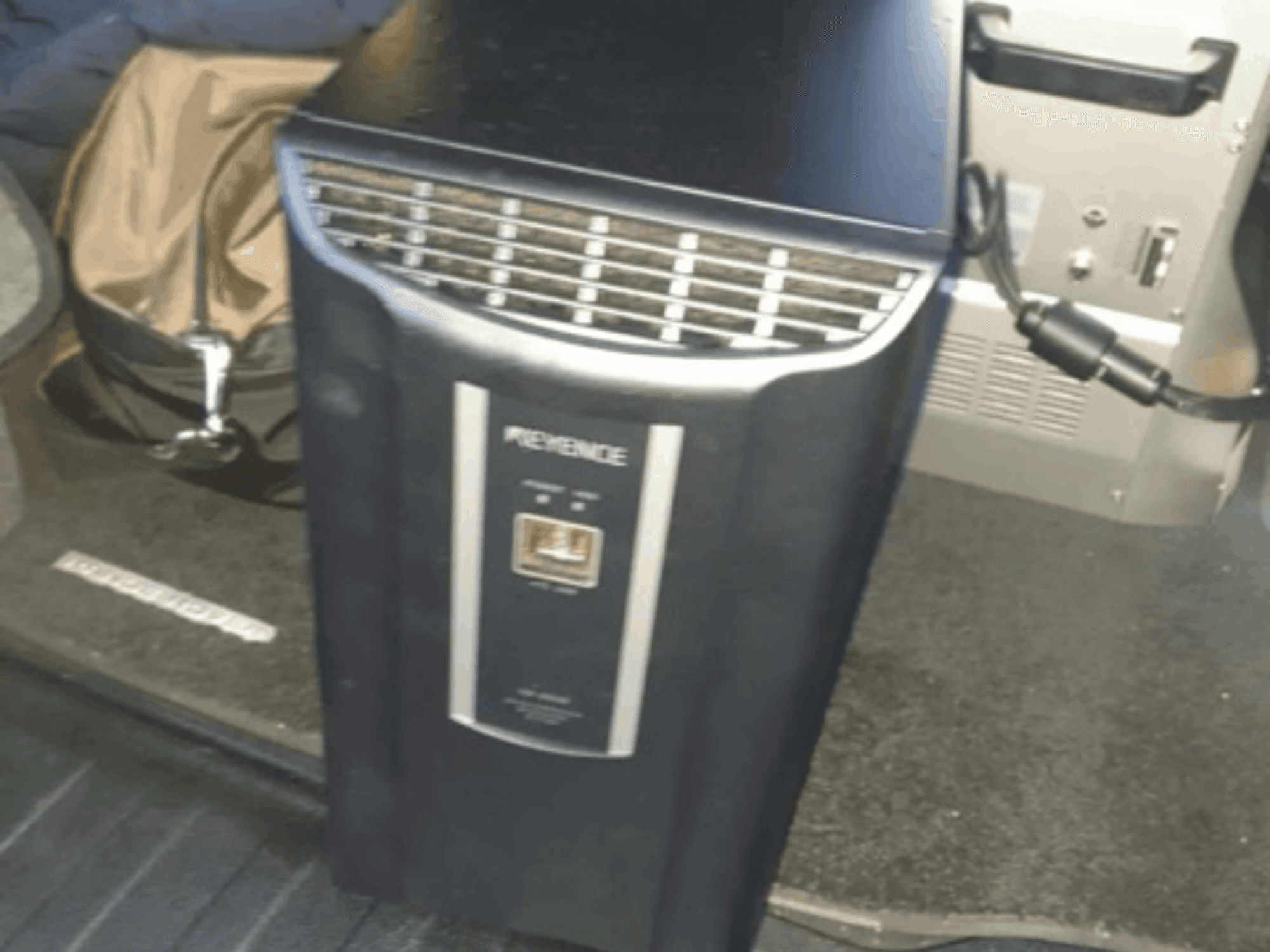 KEYENCE IM-8030 otomasyon sistemi önden görünümde, kontrol paneli ve havalandırma delikleri araç içi fonunda gösterilmektedir.