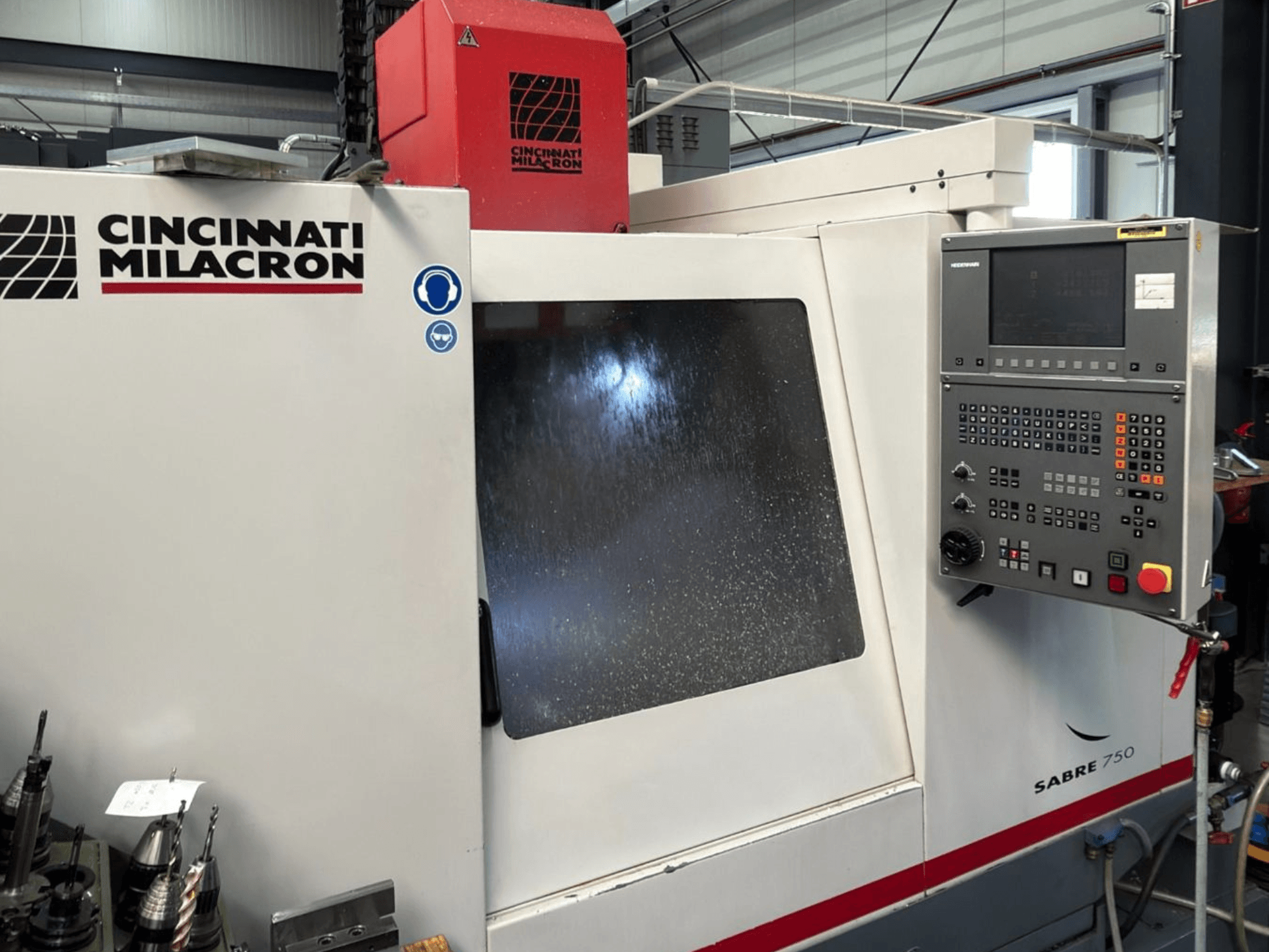 Cincinnati Milacron Sabre 750 dikey işleme merkezi, önden görünüm; kontrol paneli ve kısmen gizlenmiş cam ile.