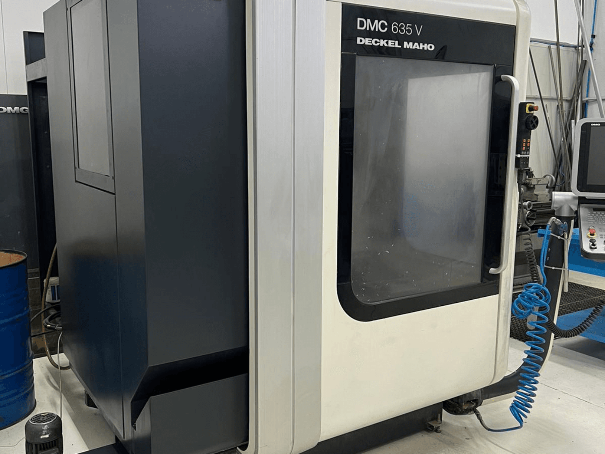 Deckel Maho'nun DMC 635 V freze makinesi, kontrol panelini ve kısmen açık erişim kapısını gösteren yandan görünüm.