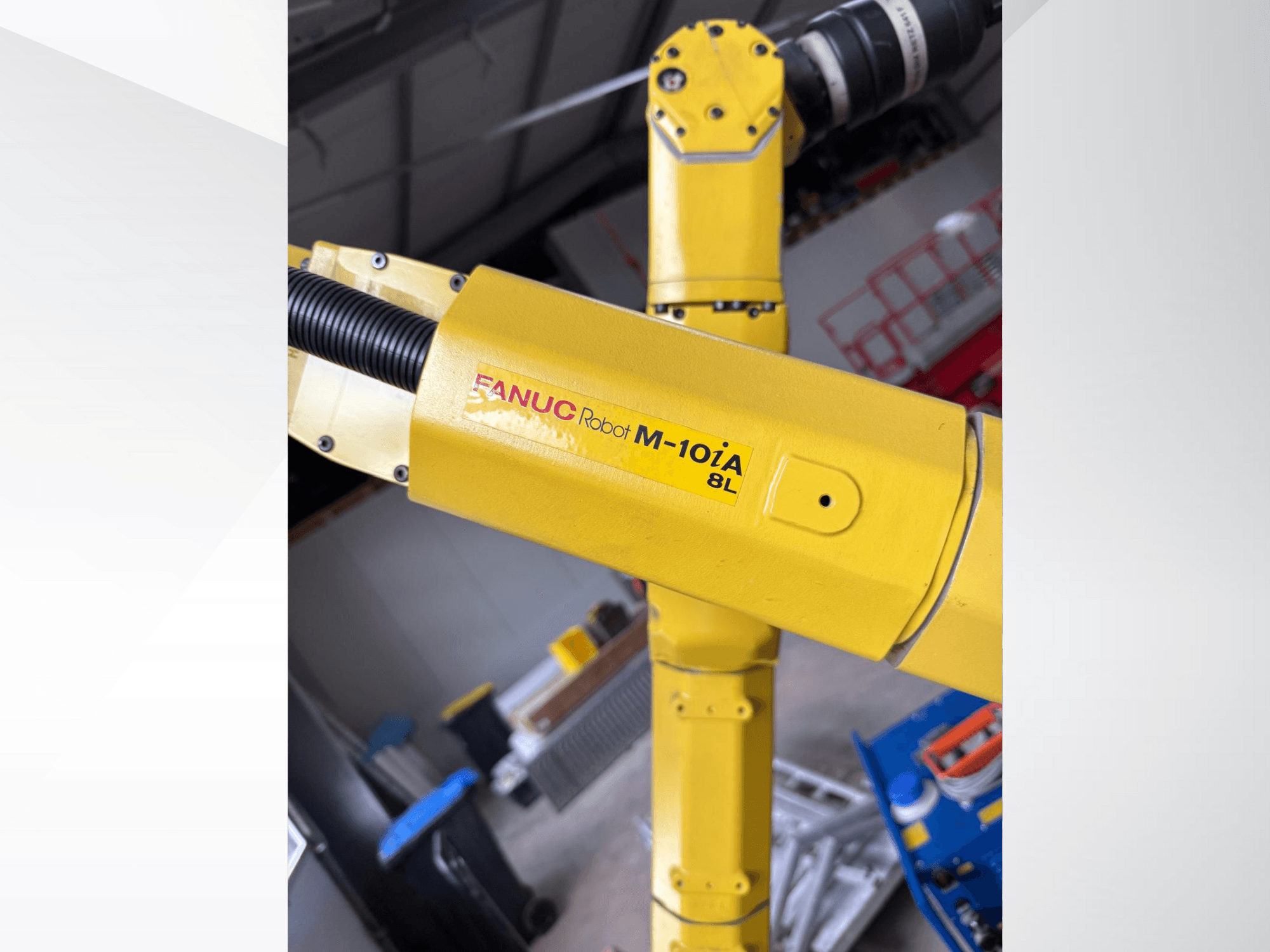 Sarı renkli FANUC Robot M-10iA 8L, yandan bakıldığında kol eklemini ve mekanik bileşenleri endüstriyel bir ortamda sergiliyor.