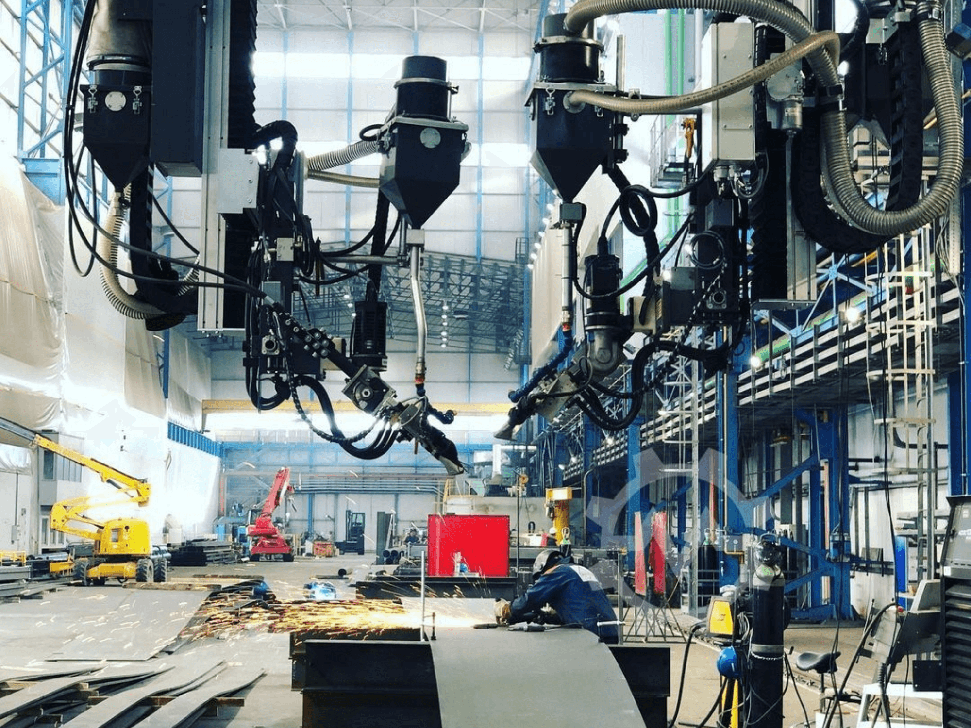 Endüstriyel bir ortamda, kıvılcımların uçuştuğu, yandan görülen robotik kesme makinesi; birden fazla ataşman ve hortum içerir.