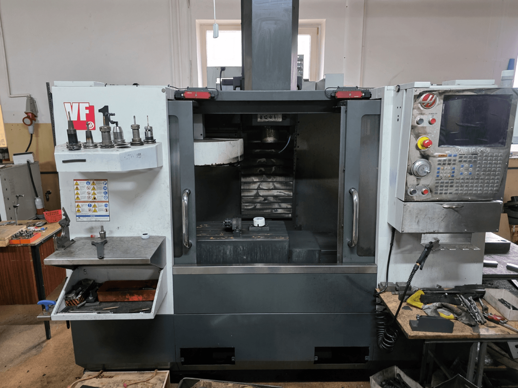 Haas VF serisi CNC freze makinesi, önden görünüm; birden fazla takım tutucu, kontrol paneli ve görünür çalışma alanına sahiptir.