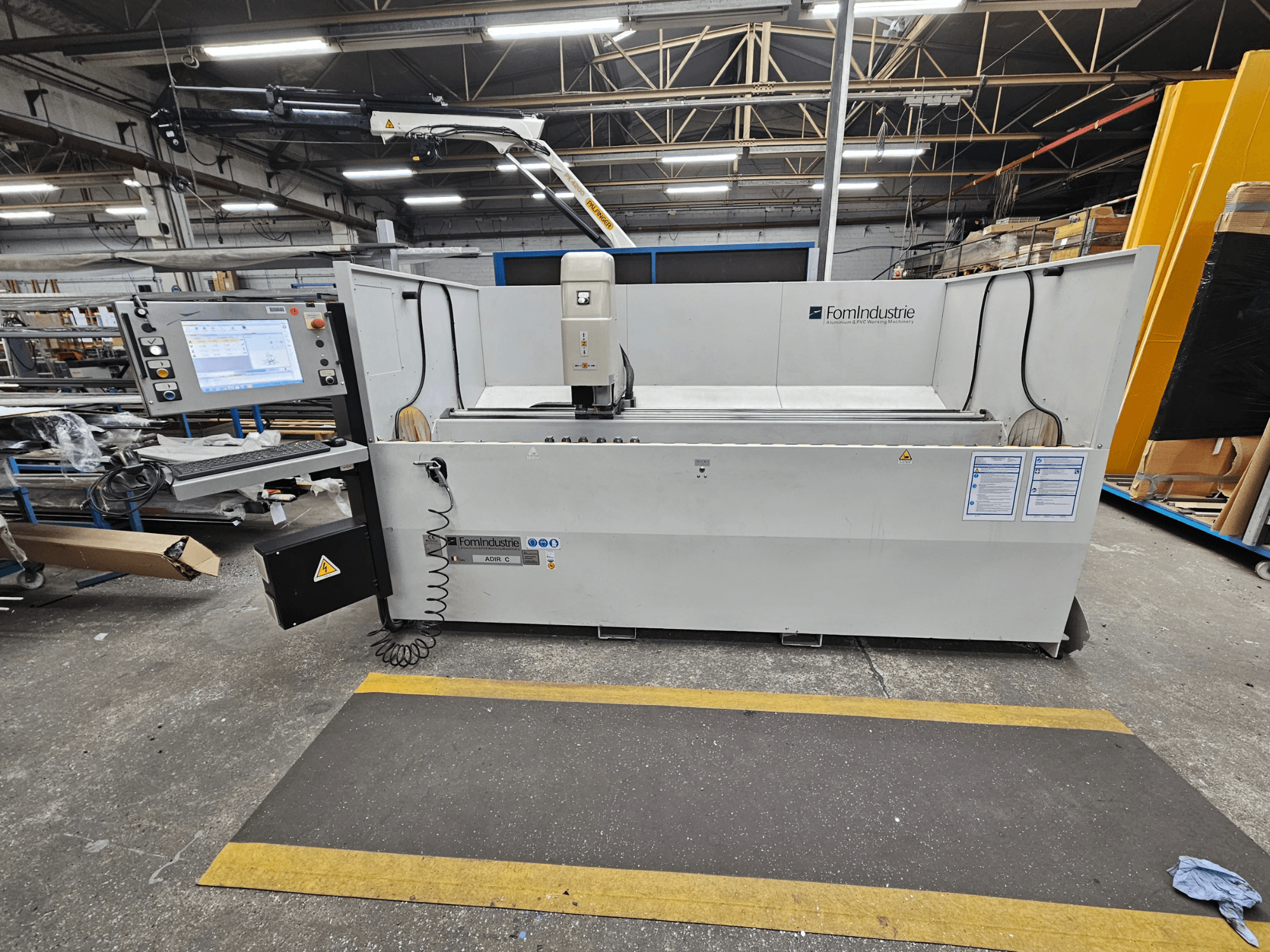 Bir atölyedeki FomIndustrie ADIR C dik işleme merkezi, kontrol paneli ve makine detaylarını gösteren önden görünüm.