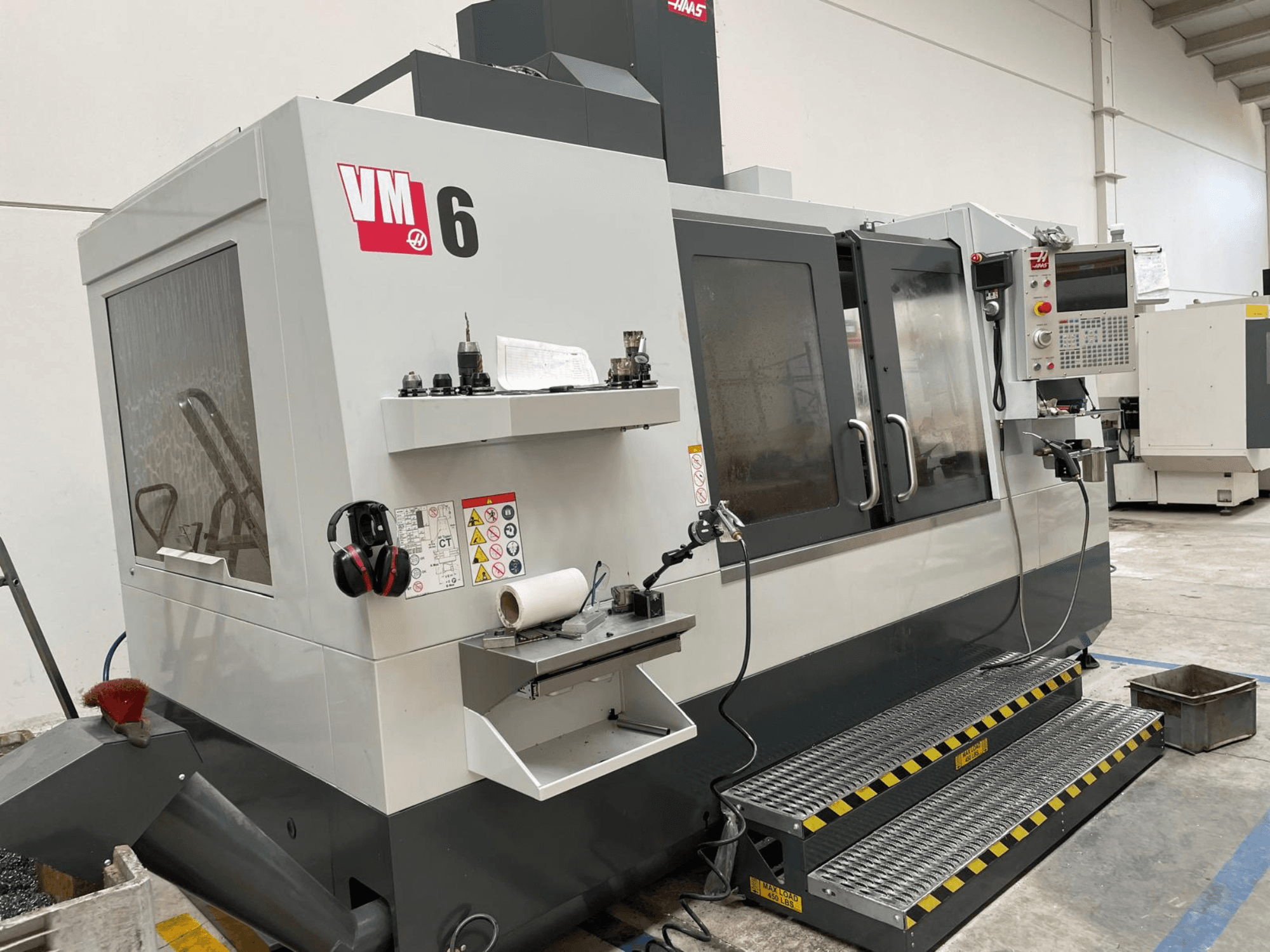 Haas VM-6 dikey işleme merkezi, kontrol panelini, takım tutucuları ve güvenlik özelliklerini gösteren önden görünüm.