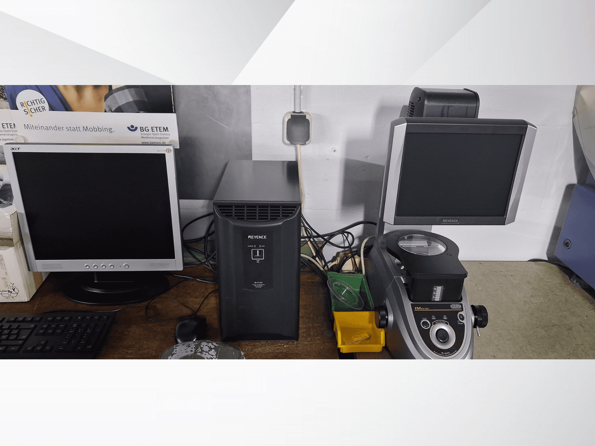 Biri Acer diğeri Keyence olmak üzere iki bilgisayar monitörü, siyah bir cihazın yanında ve önden bakıldığında bir mikroskop.