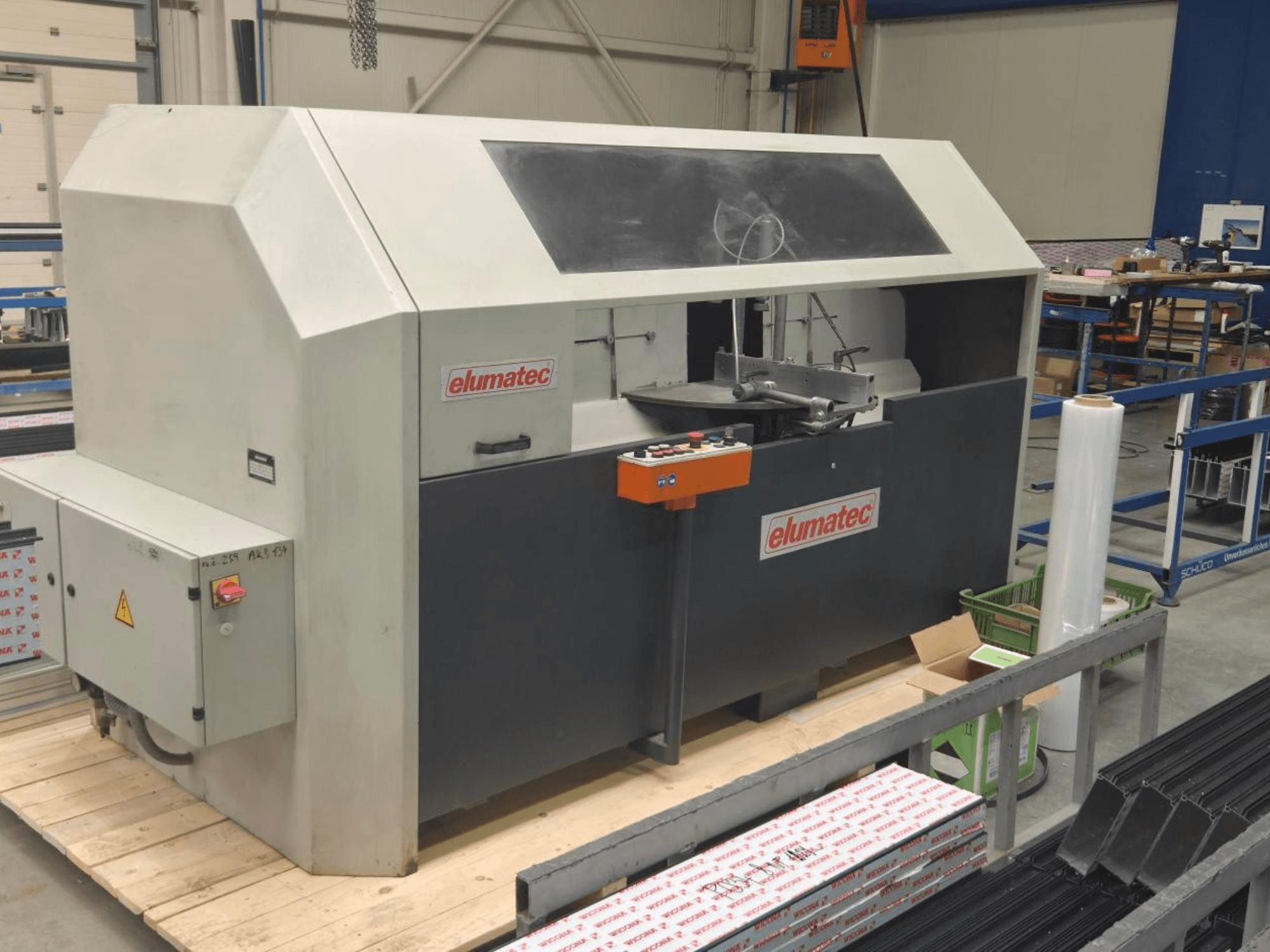 Elumatec AKS 134 dairesel metal testeresi, önden görünüm, kontrol paneli ve ahşap platform üzerindeki kesim alanı.