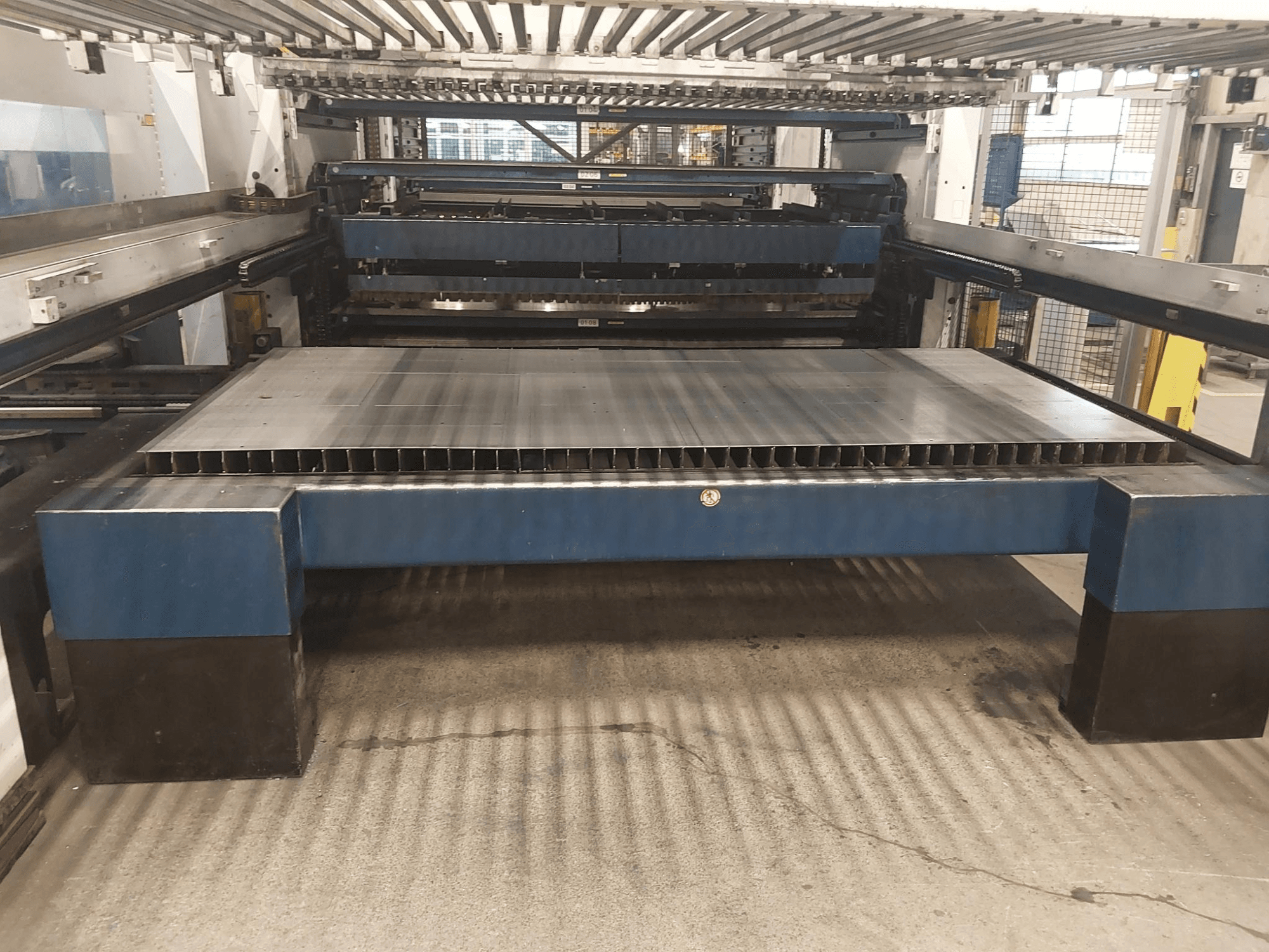 TRUMPF TruLaser 3030 L20 CO2 lazer kesim makinasının büyük kesim yatağı ve destek yapısı ile önden görünümü.