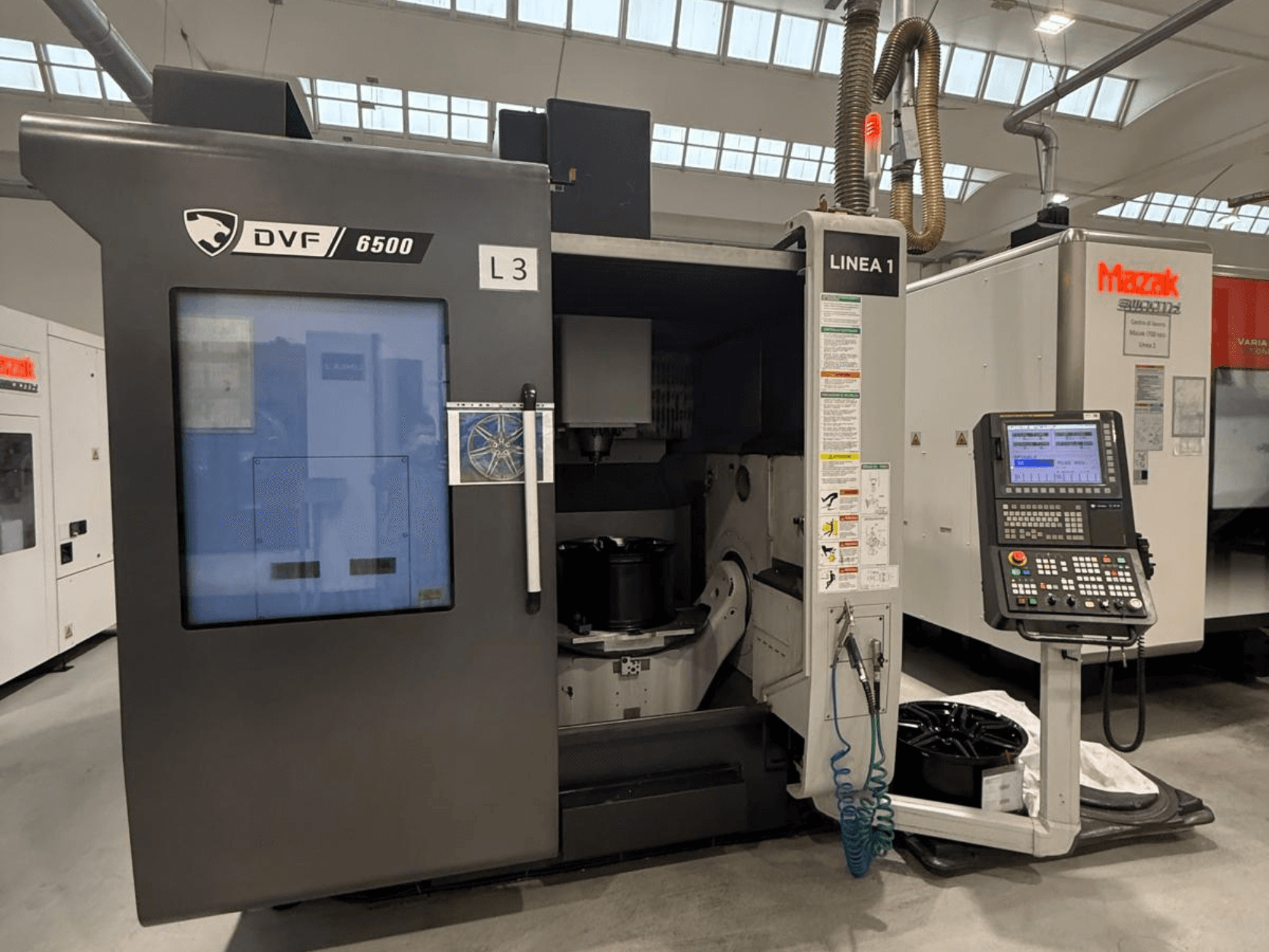 DVF 6500 CNC makinesi, önden görünüm, kontrol panelini ve bir parça fikstürü ile iç alanı gösterir.