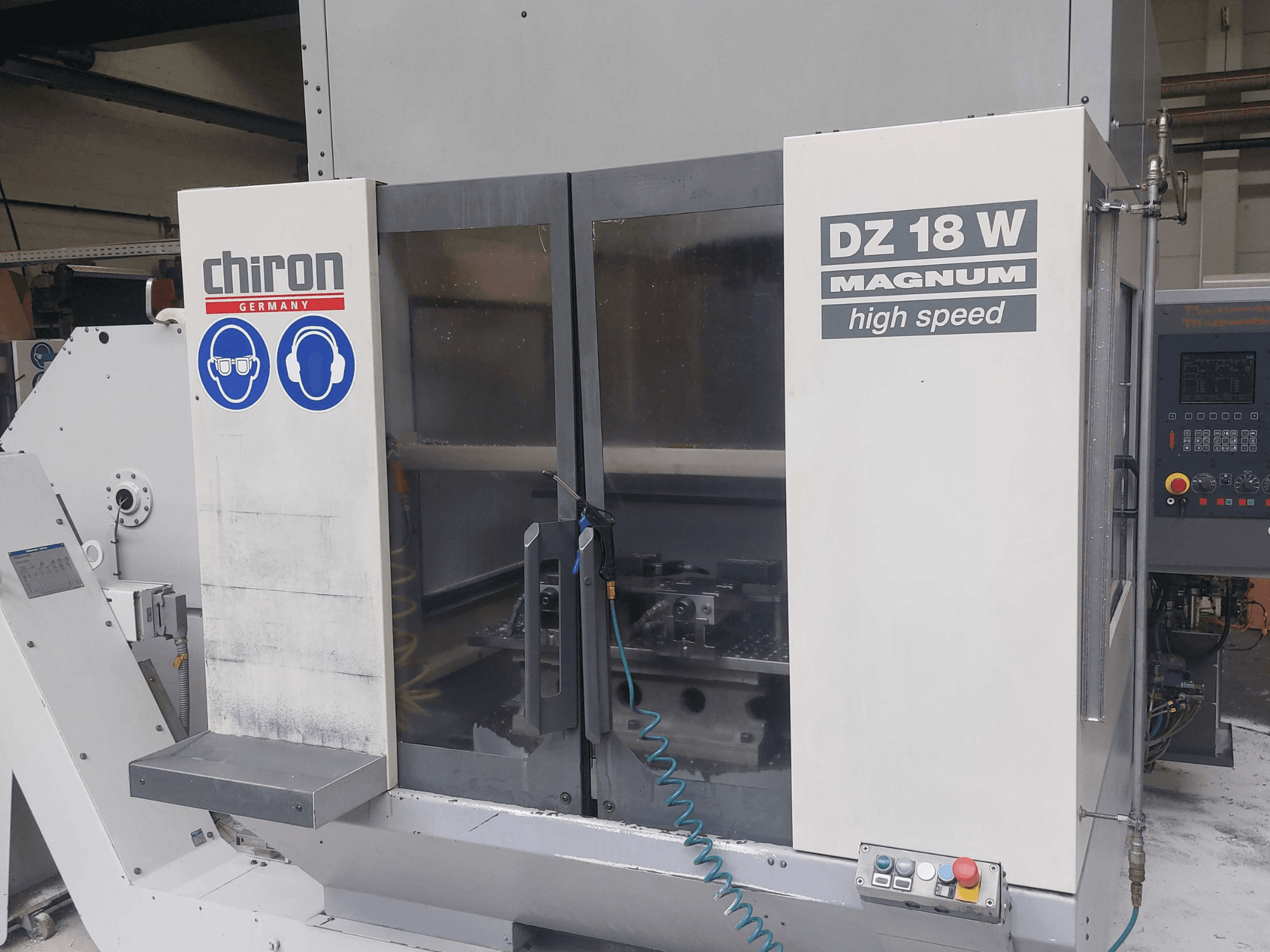 CHIRON DZ 18 W MAGNUM dikey işleme merkezi; kontrol paneli ve güvenlik işaretlerini gösteren önden görünüm.