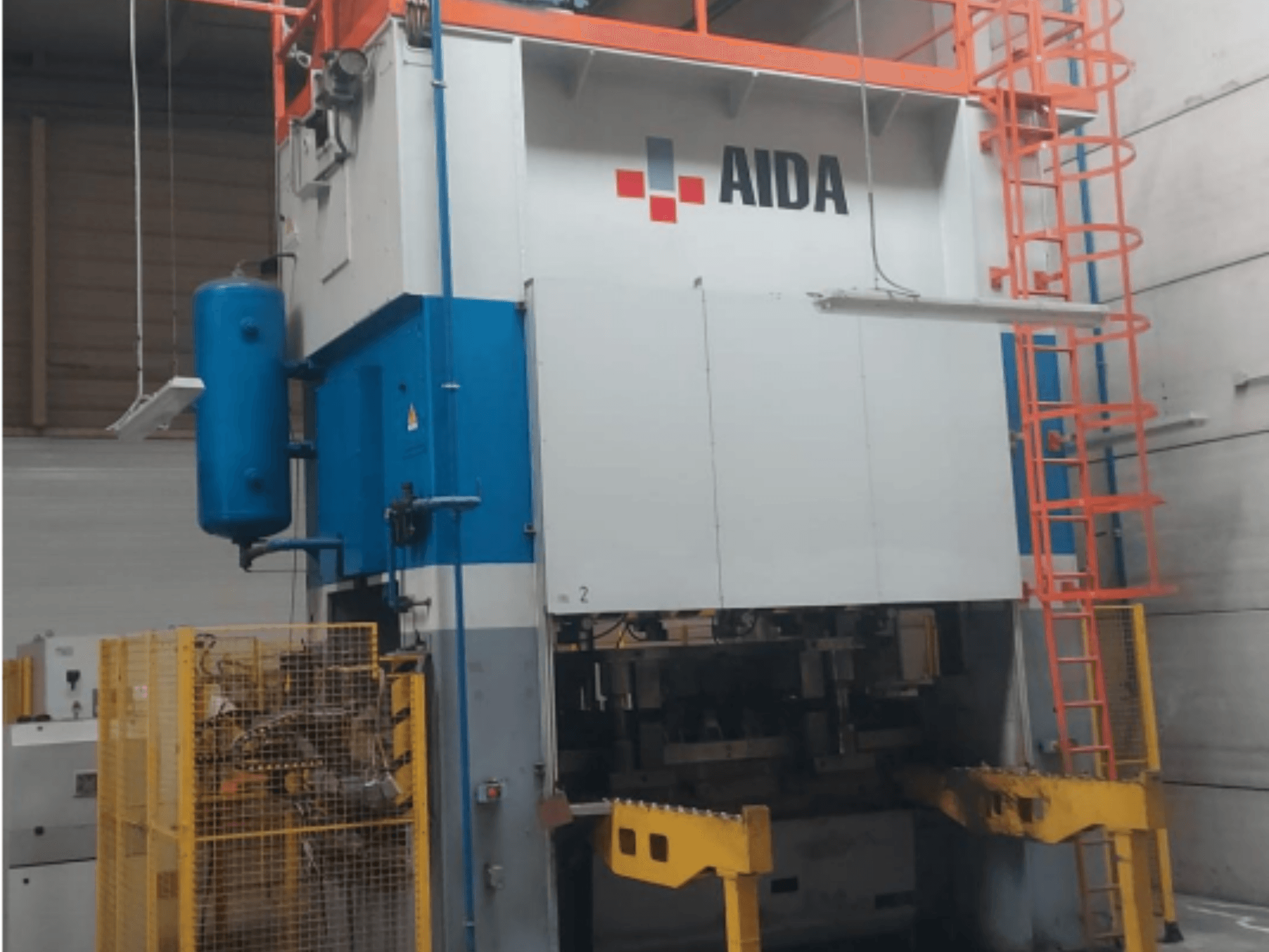 Mekanik damgalama presi AIDA 315/2MR/LD/TE 3, mavi ve beyaz gövde, sarı taban ve güvenlik kafesi ile önden görünüm.