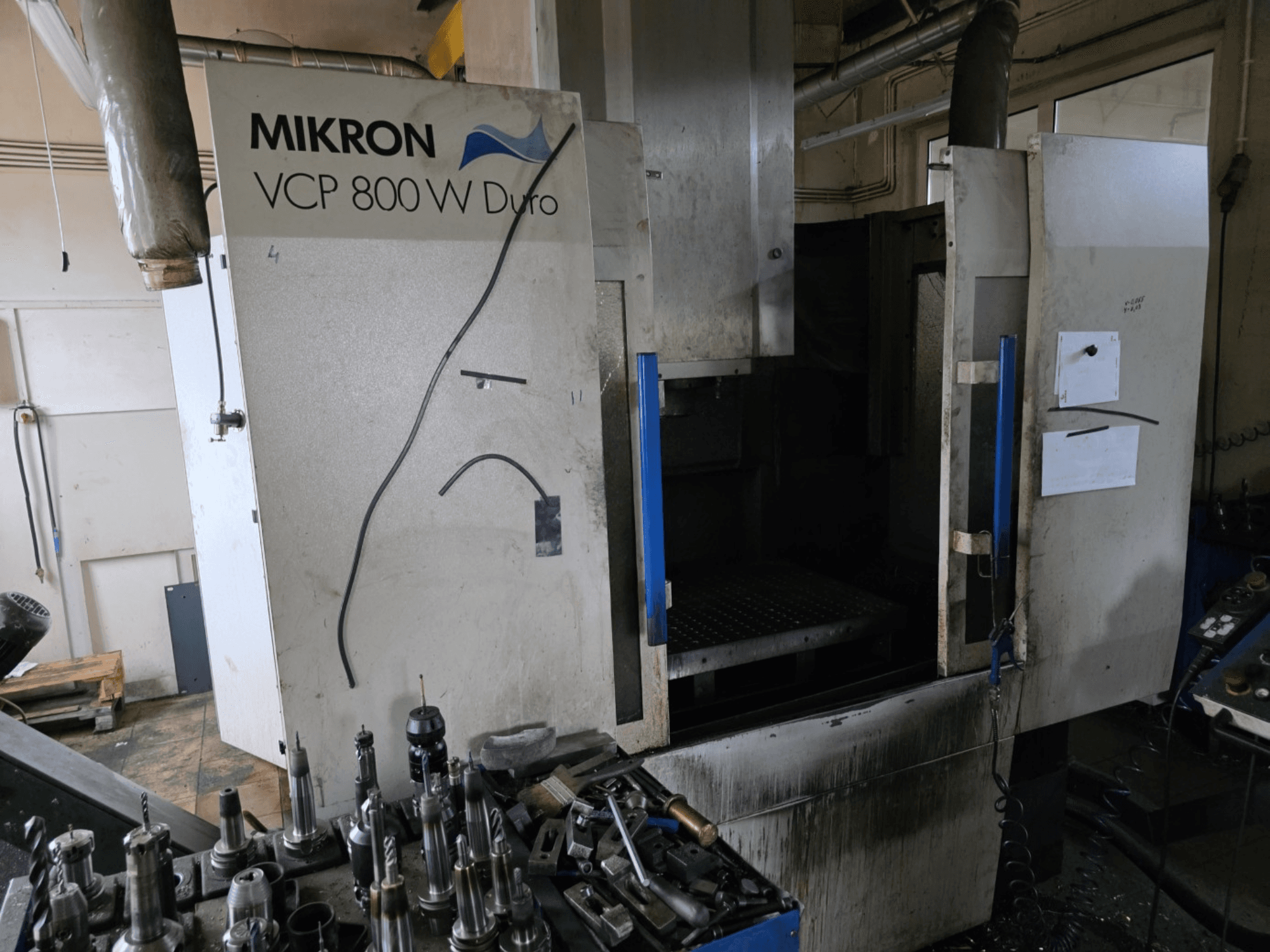Mikron VCP 800 W Duro freze makinesi, ön planda görünen takımlar ve kontroller ile yandan gösterilmiştir.