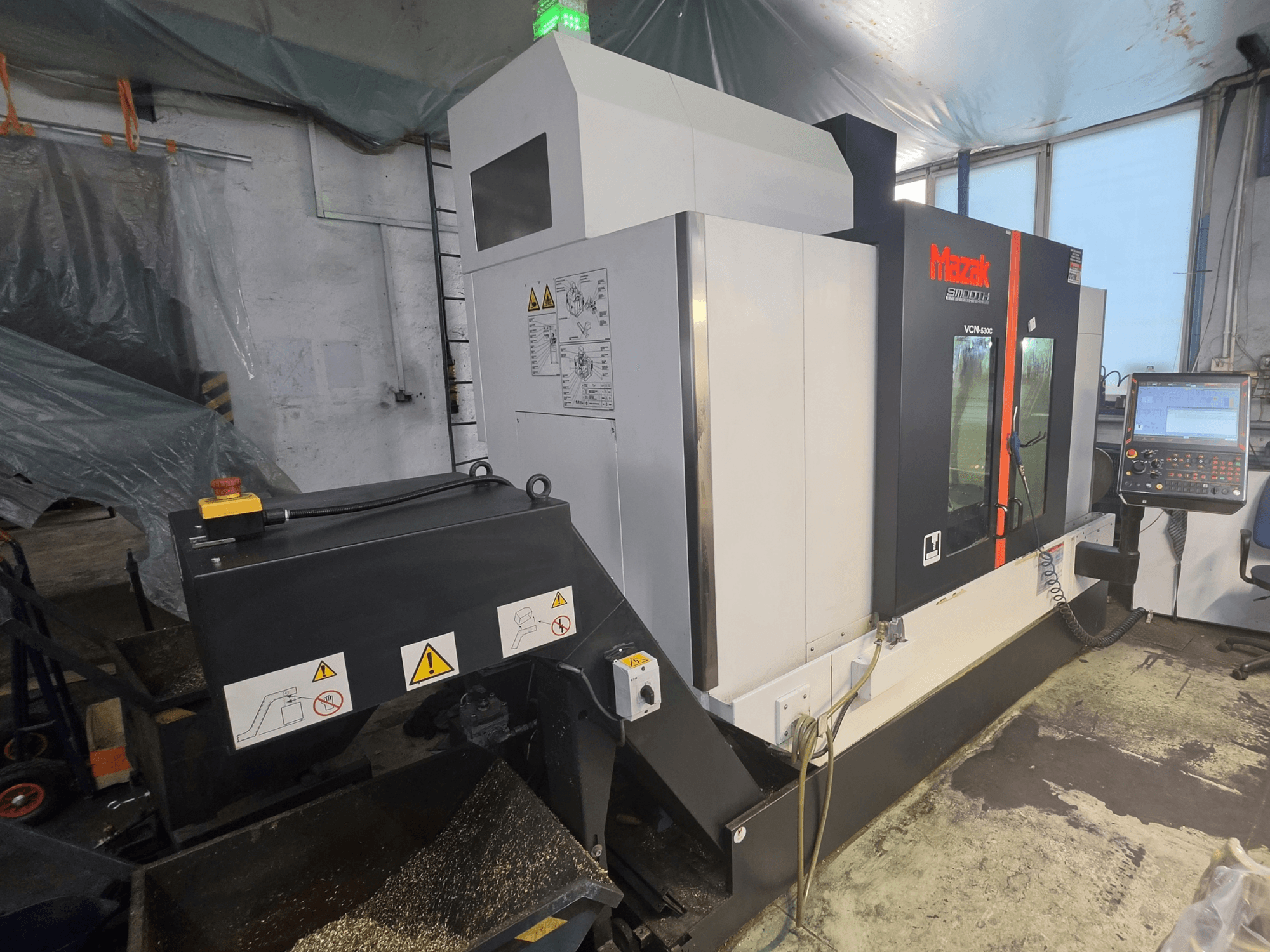 Mazak VCN-530C Dikey İşleme Merkezi’nin önden görünümü; kontrol paneli, takım zinciri ve çalışma göstergelerini göstermektedir.