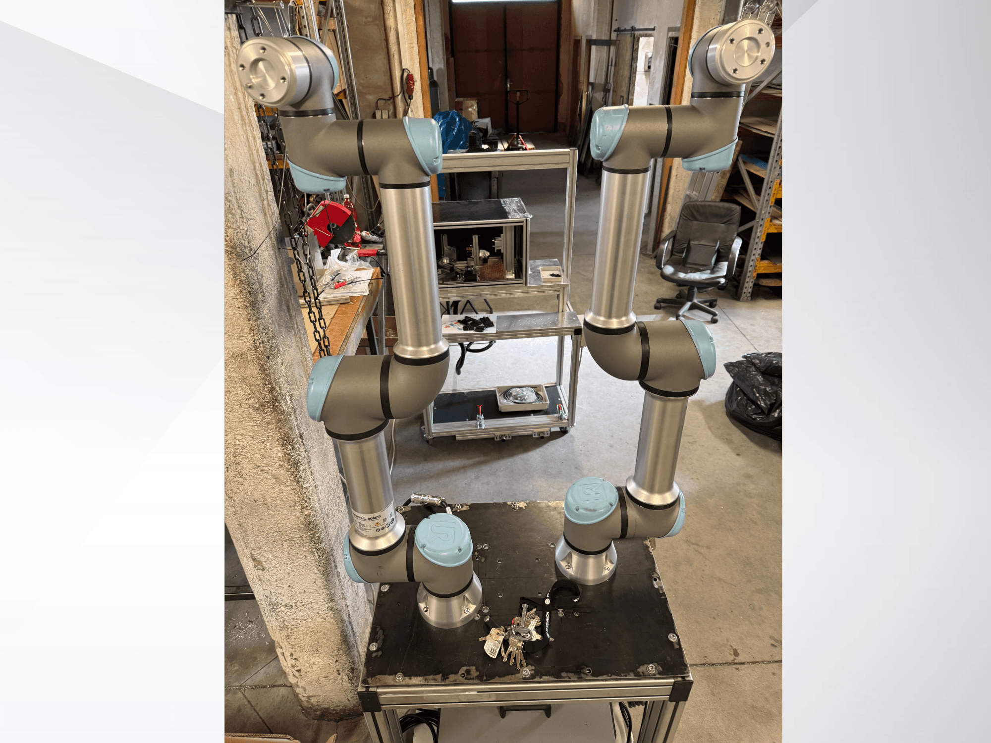 Universal Robots UR5e robot kolu, üstten görünümde gösterilmiştir; çok eklemli alüminyum yapısı ve gri-mavi renkli eklemleri göze çarpmaktadır.