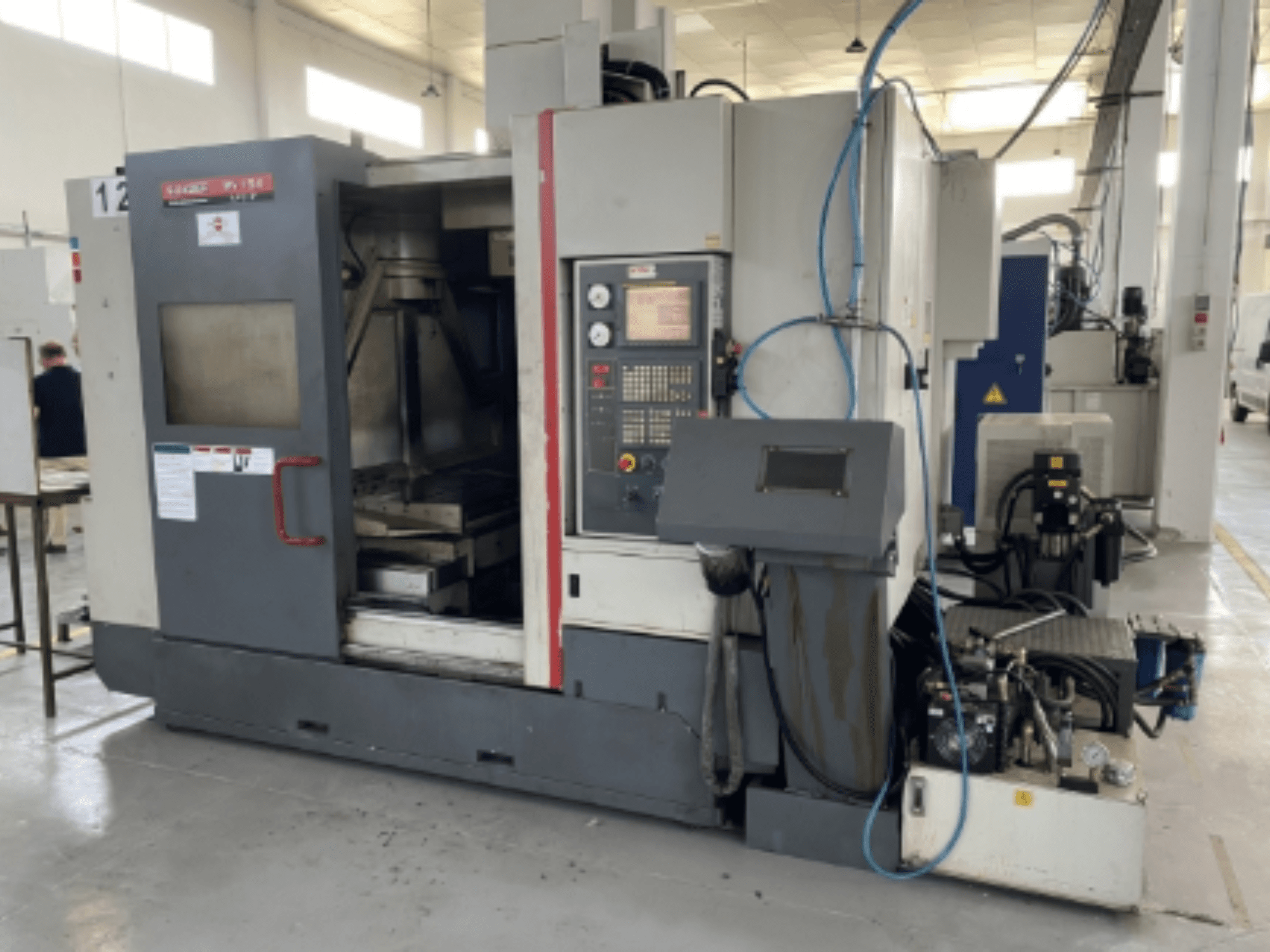 Quaser MV154APC-912 dikey işleme merkezi, kontrol paneli, açık kapı ve makine bileşenlerini gösteren önden görünüm.