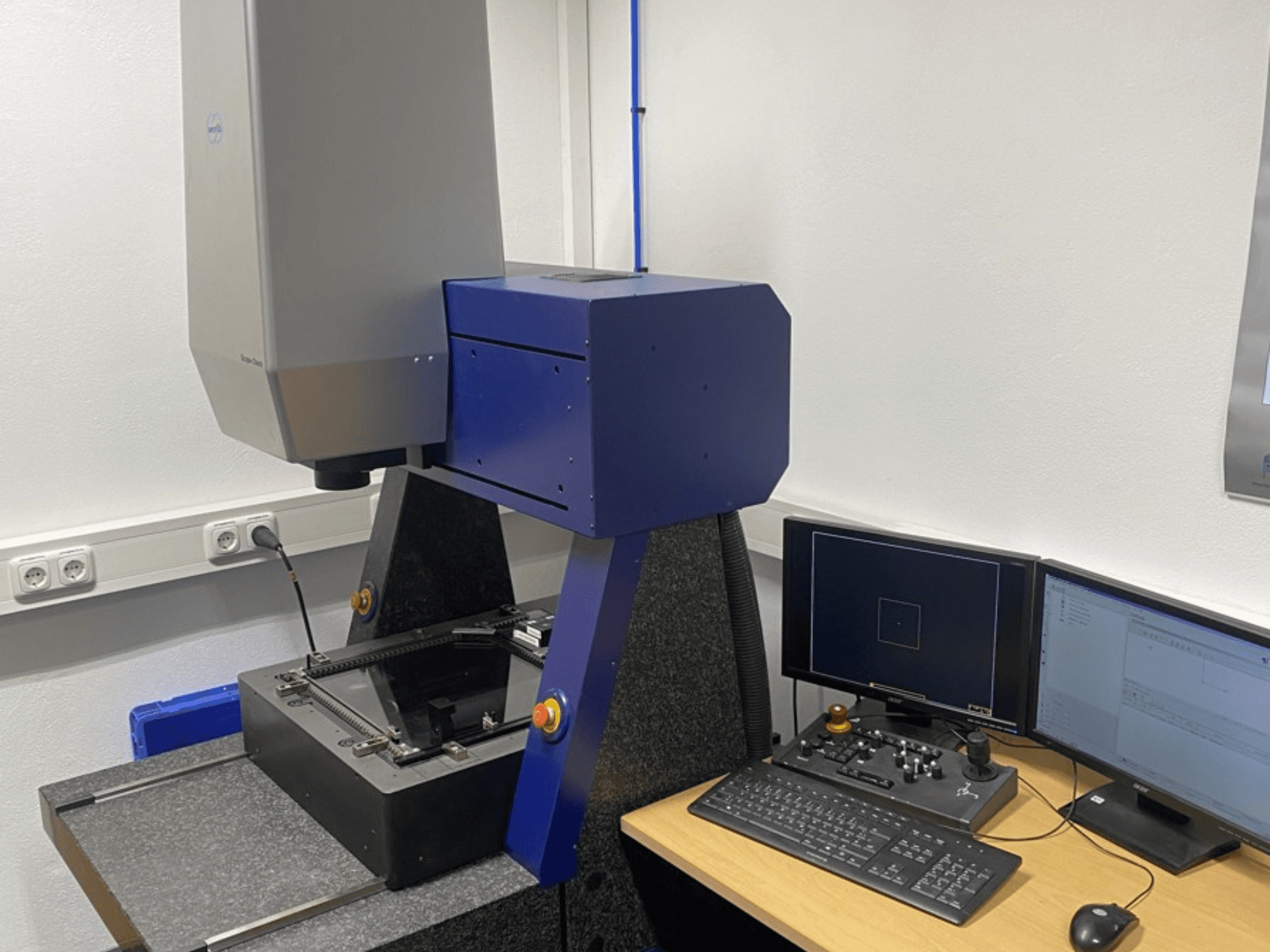 Werth Scope-Check 400 CMM bir laboratuvarda, ölçüm kafasını ve ekranlı ve klavyeli kontrol panelini göstermektedir.