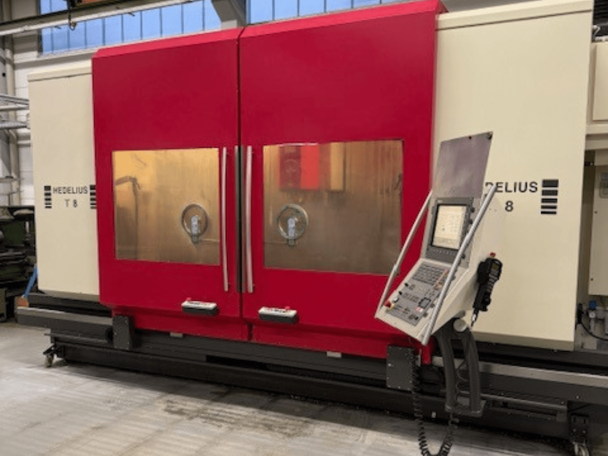 HEDELIUS T8 CNC makinesinin önden görünümü, kırmızı kapılar, kontrol paneli ve iç bileşenlerin görünürlüğü.