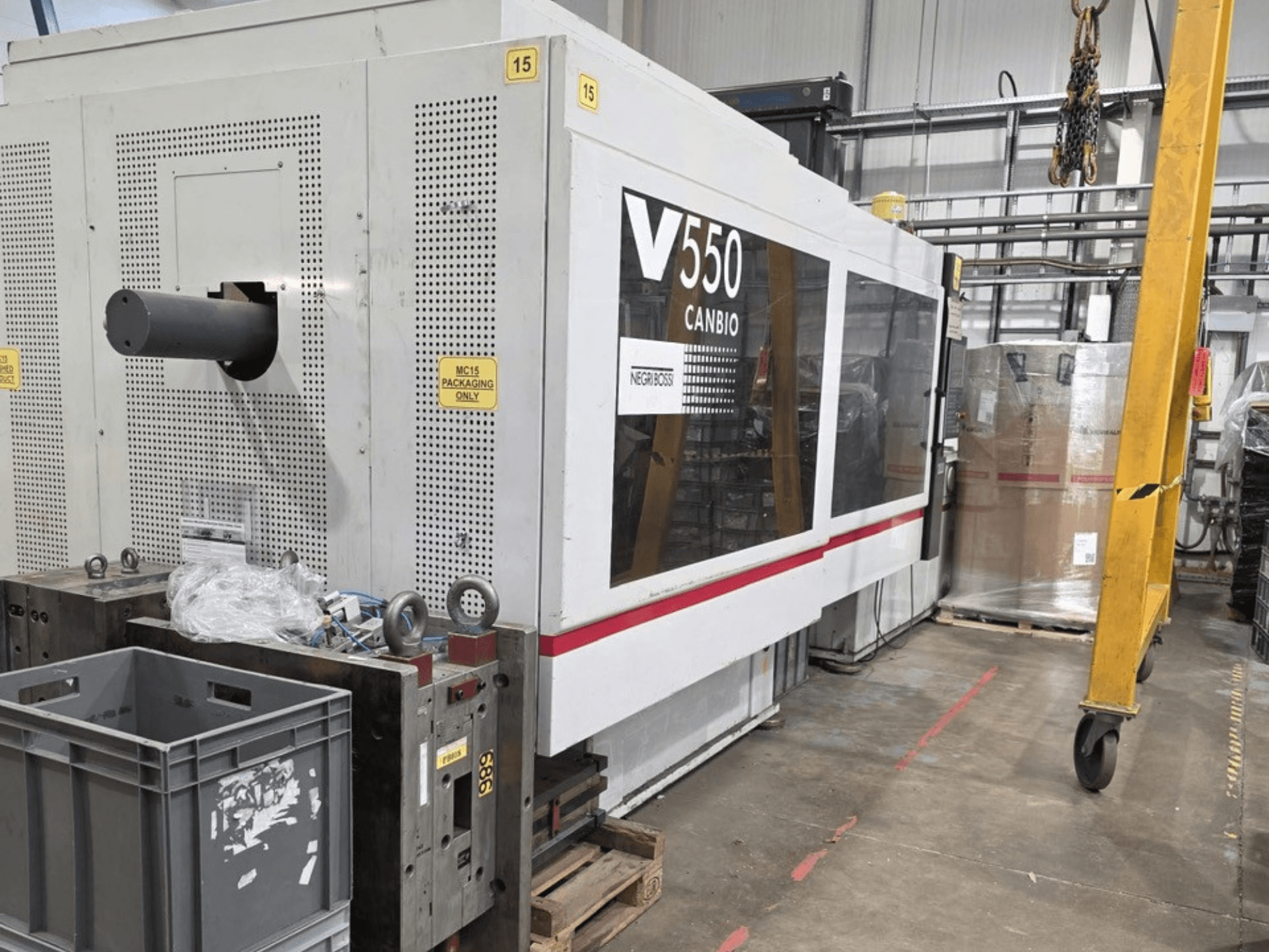 Negri Bossi V55000H-4250 hidrolik enjeksiyon kalıplama makinesi, yandan görünüm, kontrol paneli ve ön planda gri kasalar.