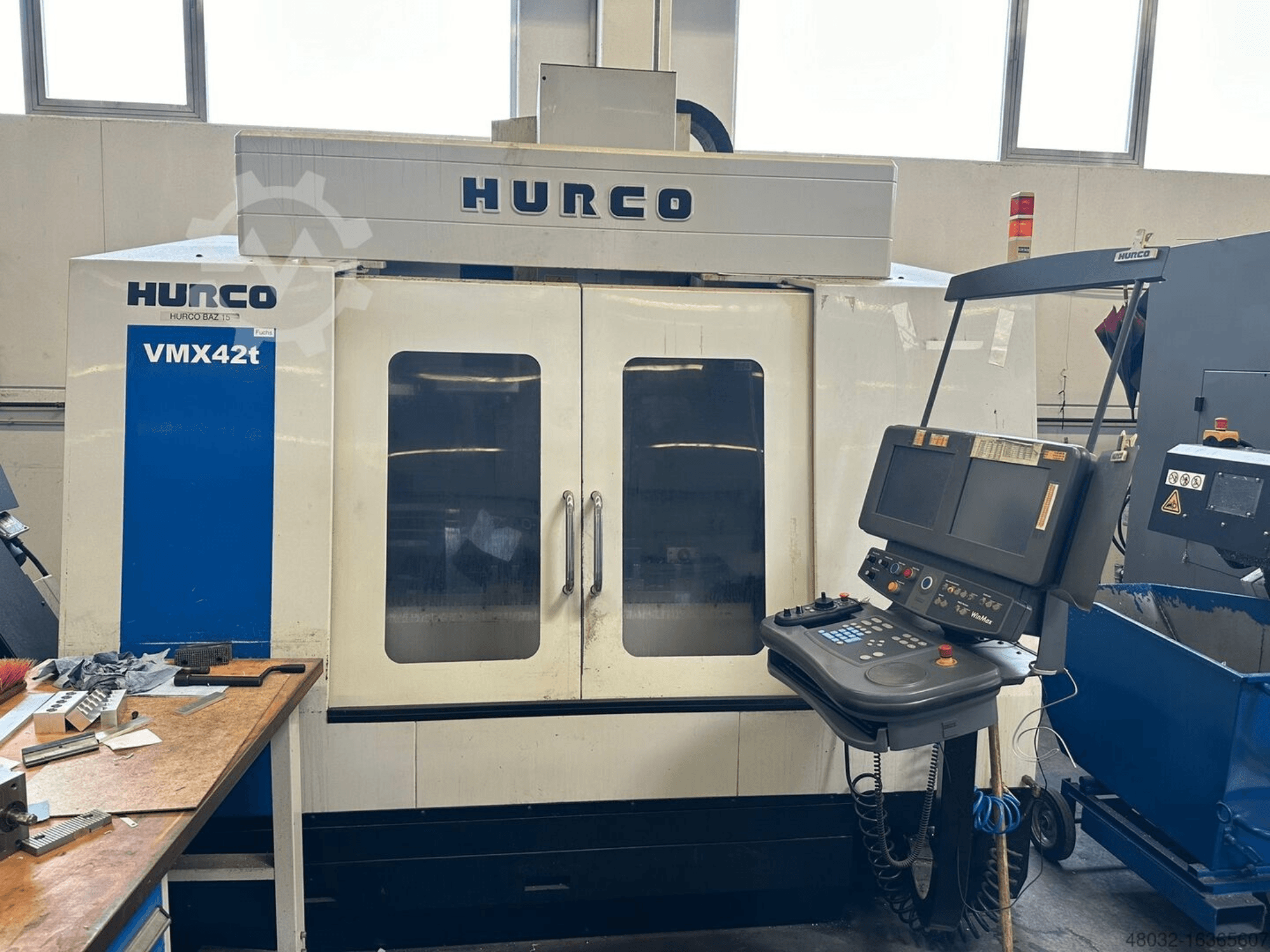 Hurco VMX42t Dikey İşleme Merkezi, önden görünüm; kontrol paneli ve takımlarla işlenmekte olan iş parçalarının görülebildiği iç kısım.
