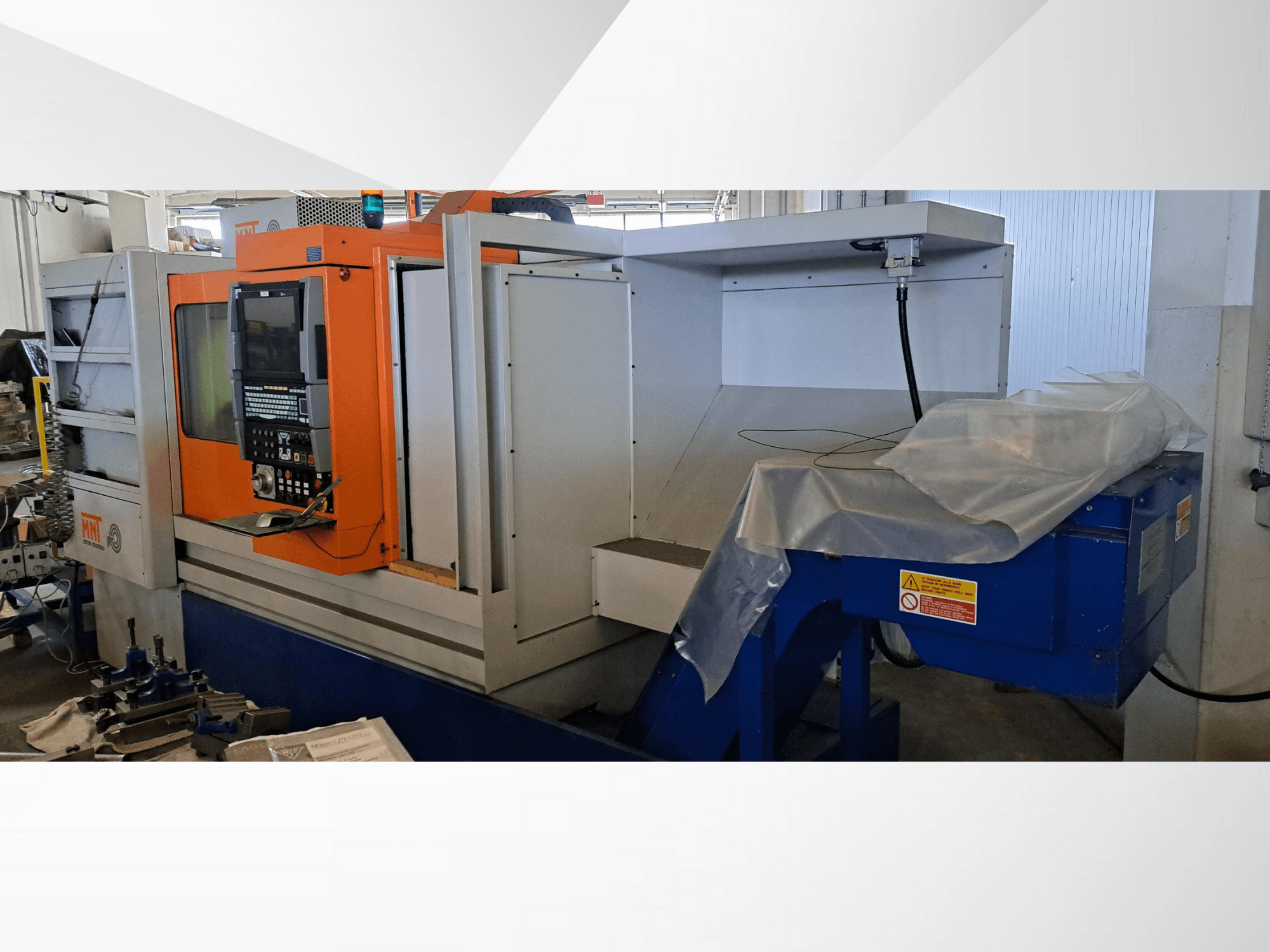 MNT CNC makinesi, önden görünüm, turuncu kontrol paneli, geniş işleme alanı ve mavi talaş atma ünitesi.
