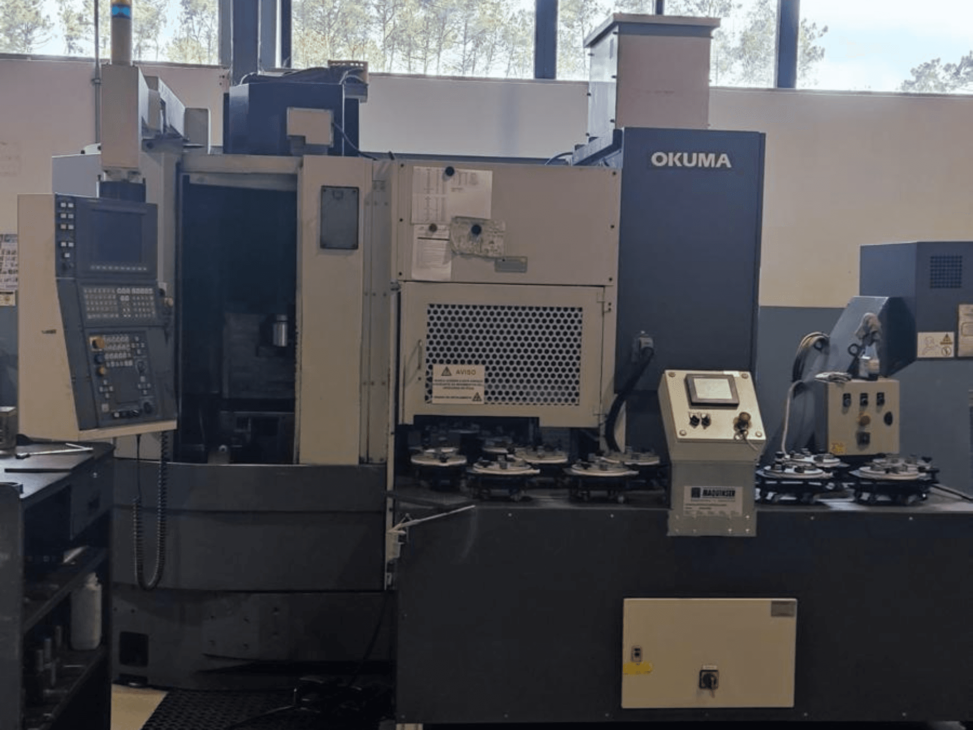 Okuma LVT300 dikey torna makinesinin önden görünümü, kontrol paneli, takım tutucular ve işleme alanı.