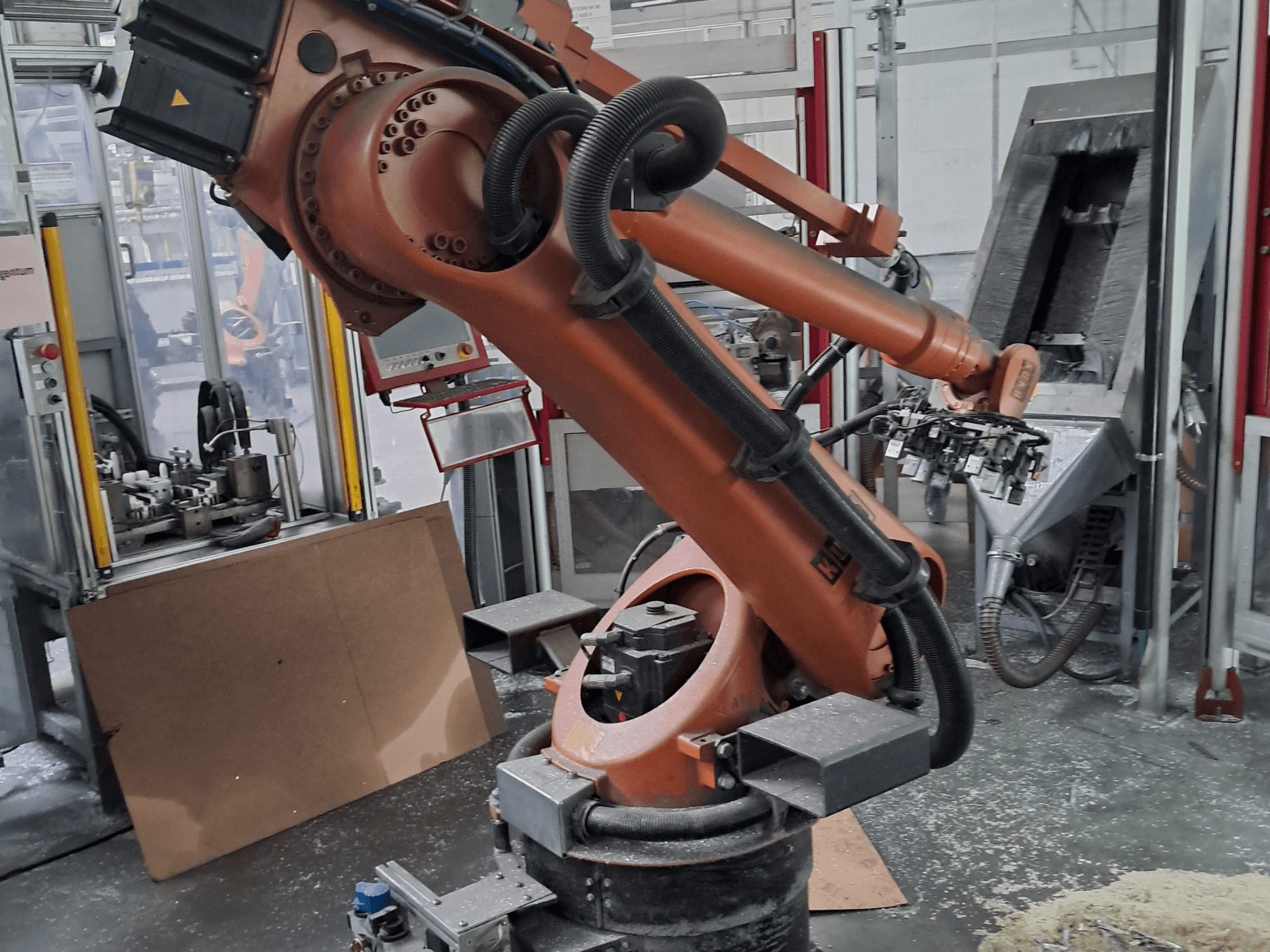 Bir atölyede bulunan KUKA KR 30 L 16-2 robot kolu, önden görünüm. Eklemli bağlantılara ve endüstriyel çalışma alanı arka planına sahiptir.