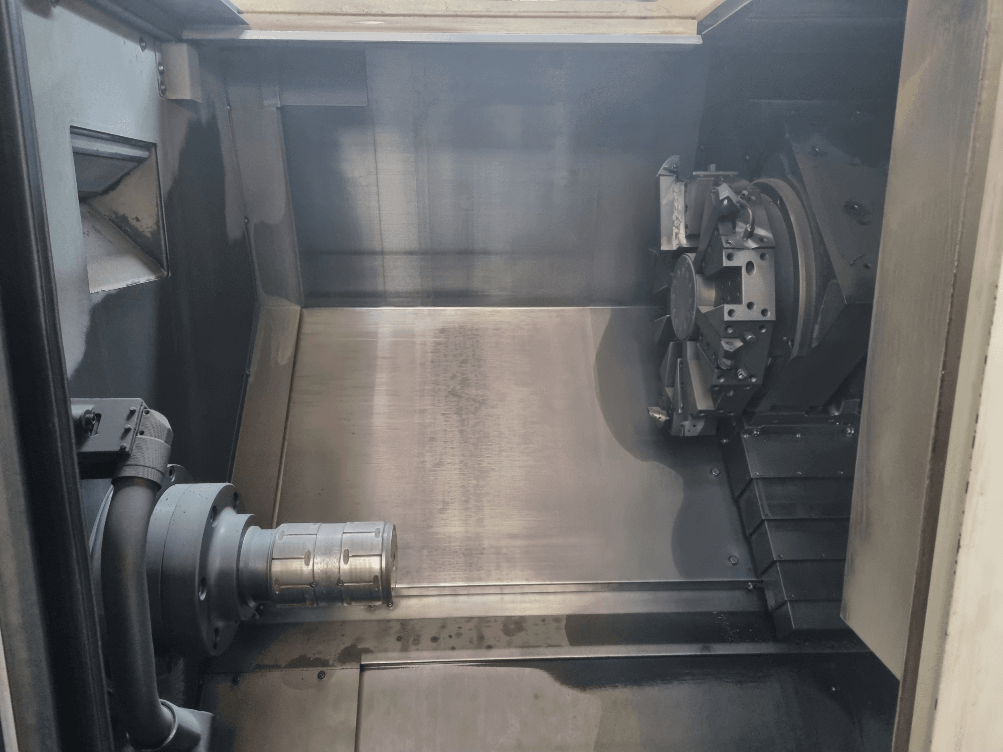 Metal çalışma alanını, takım tutucuyu ve aynayı gösteren bir CNC makinesinin iç görünümü; hassas mühendisliği vurgular.