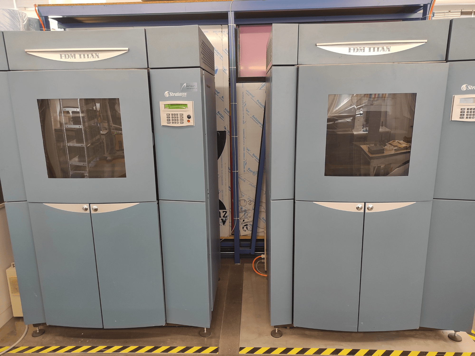 Stratasys tarafından üretilen FDM TitanTI 3D yazıcı, önden görünüm; çift kapı ve kontrol paneli ile birlikte endüstriyel bir ortamda yer almaktadır.