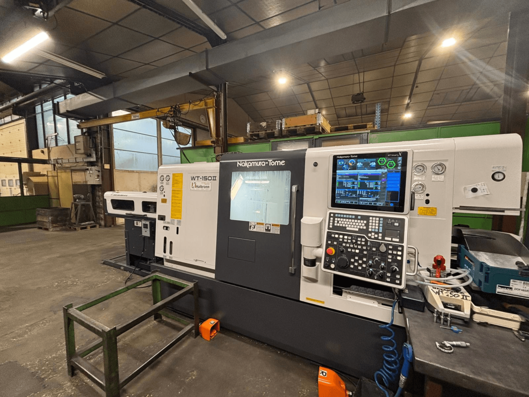 Nakamura-Tome WT-150II makinesi, önden görünüm, kontrol paneli ve aletler atölye ortamında bir tezgah üzerinde görülebilir.