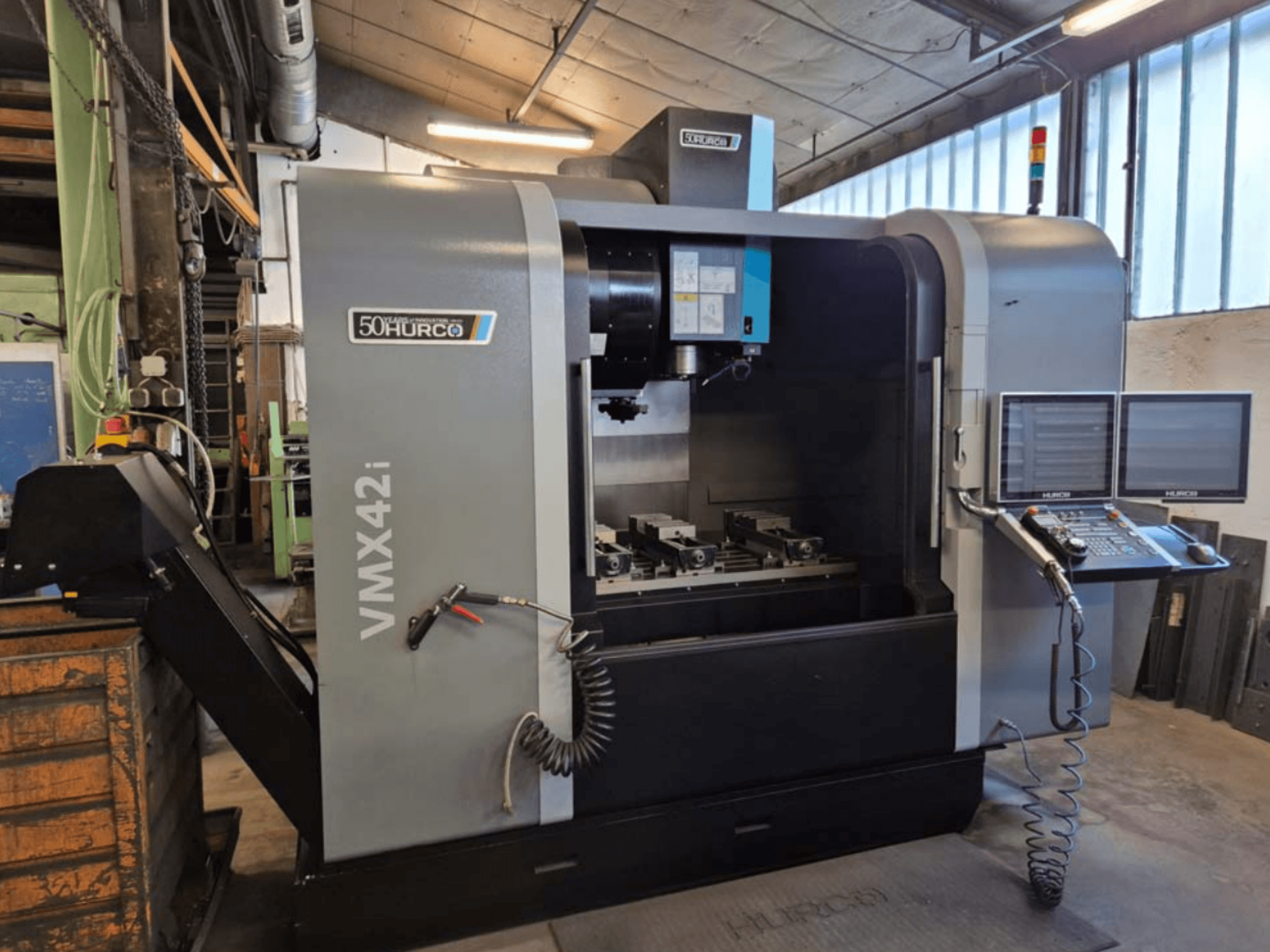 Hurco VMX 42i dikey işleme merkezi, önden görünüm, kontrol paneli ve mengeneli çalışma alanı.