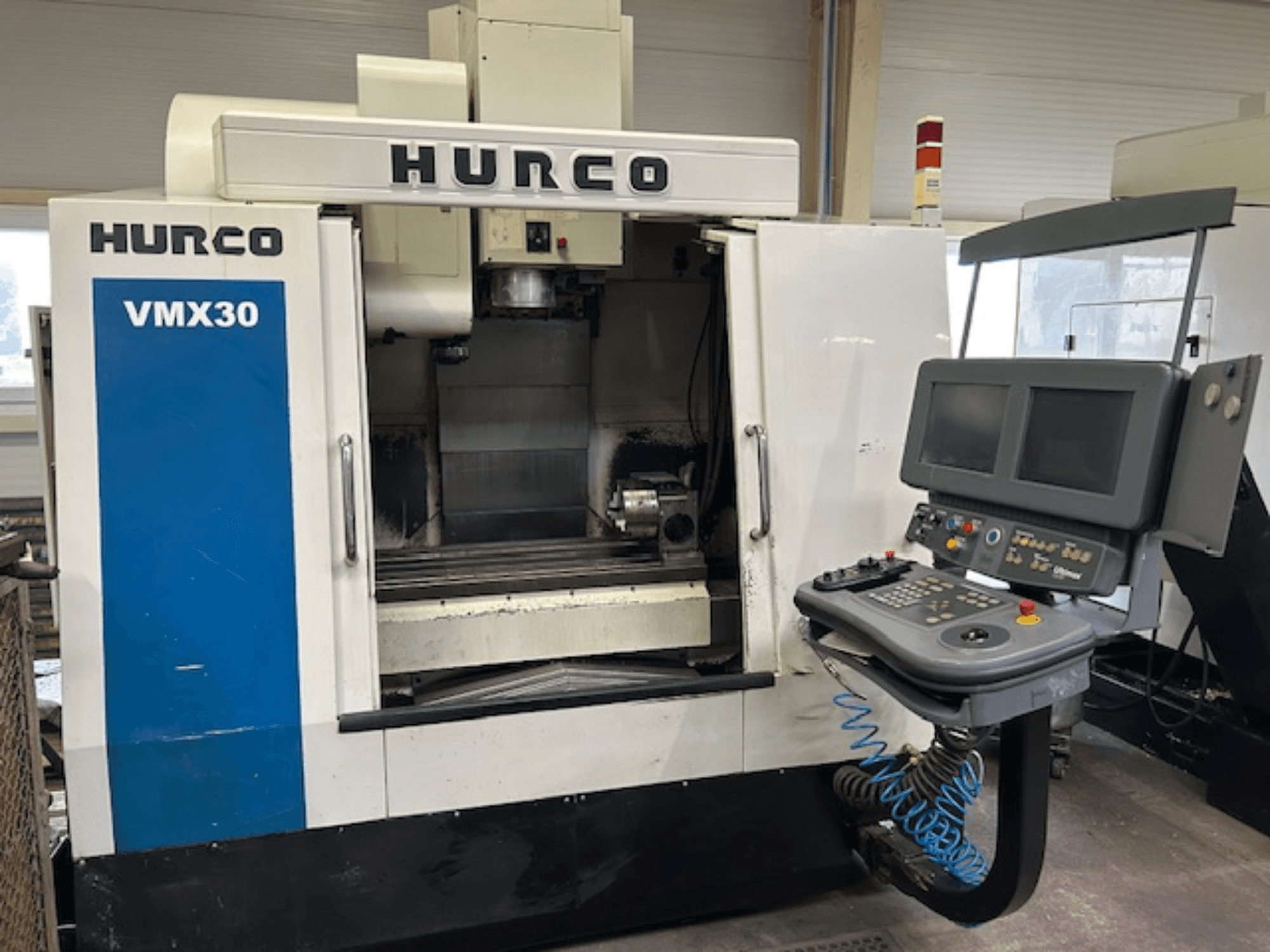 Hurco VMX30 CNC freze makinesi atölyede, önden görünüm; çift ekranlı ve operasyonel düğmeli kontrol paneline sahiptir.