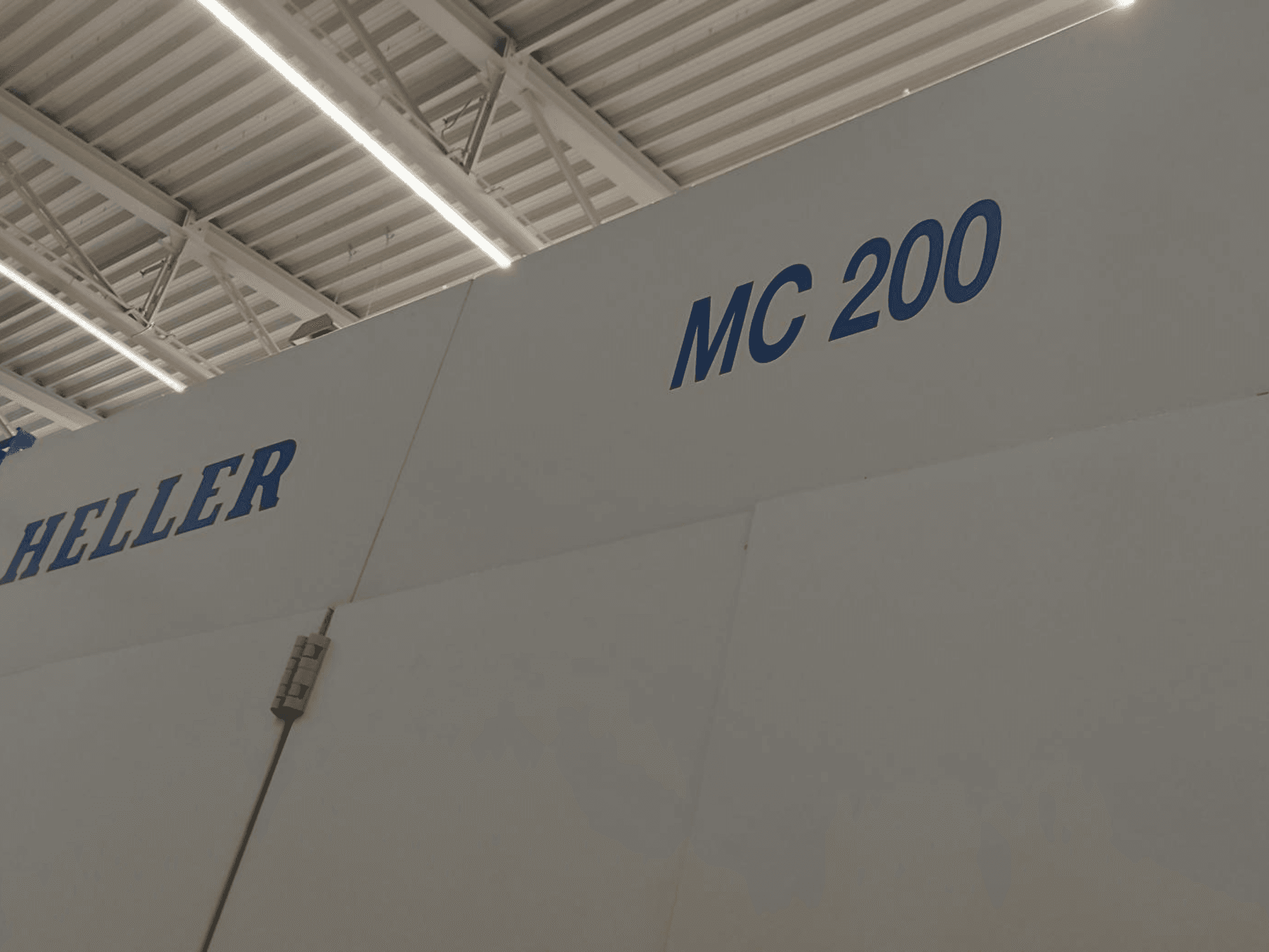 Heller MC 200 yatay işleme merkezi, yandan gösterilmiş, beyaz bir yüzey üzerinde mavi harflerle marka ve model vurgulanmıştır.