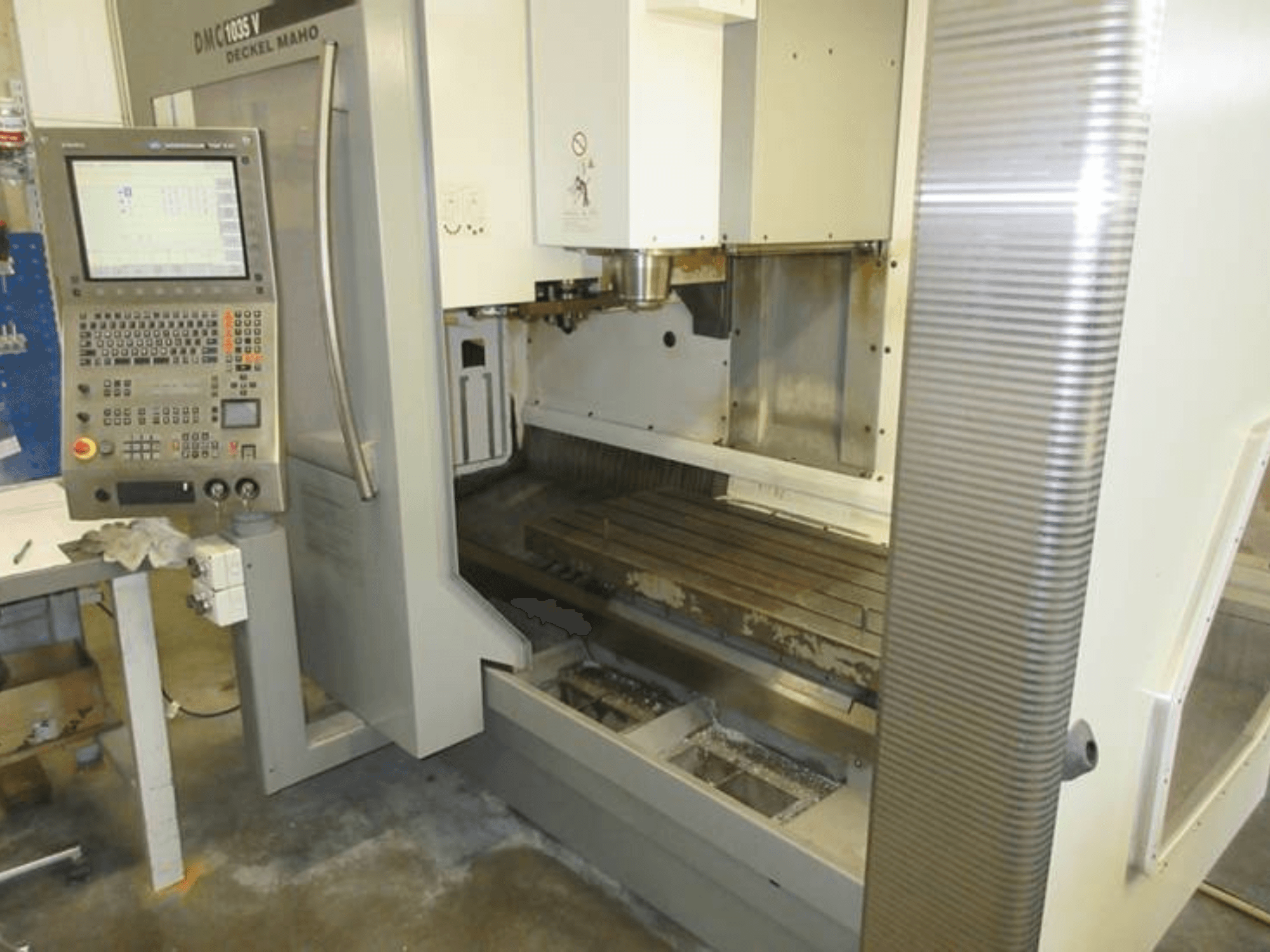 DECKEL MAHO DMC 1035 V dikey işleme merkezinin, kontrol paneli, görünen iş masası ve iş mili bölgesi ile birlikte önden görünüşü.