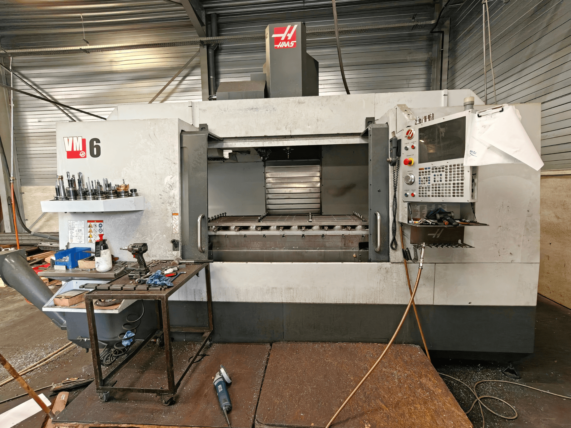 Haas VM-6 dikey işleme merkezi, önden görünüm; takım deposu, kontrol paneli ve işleme alanındaki talaşlar görülebilir.