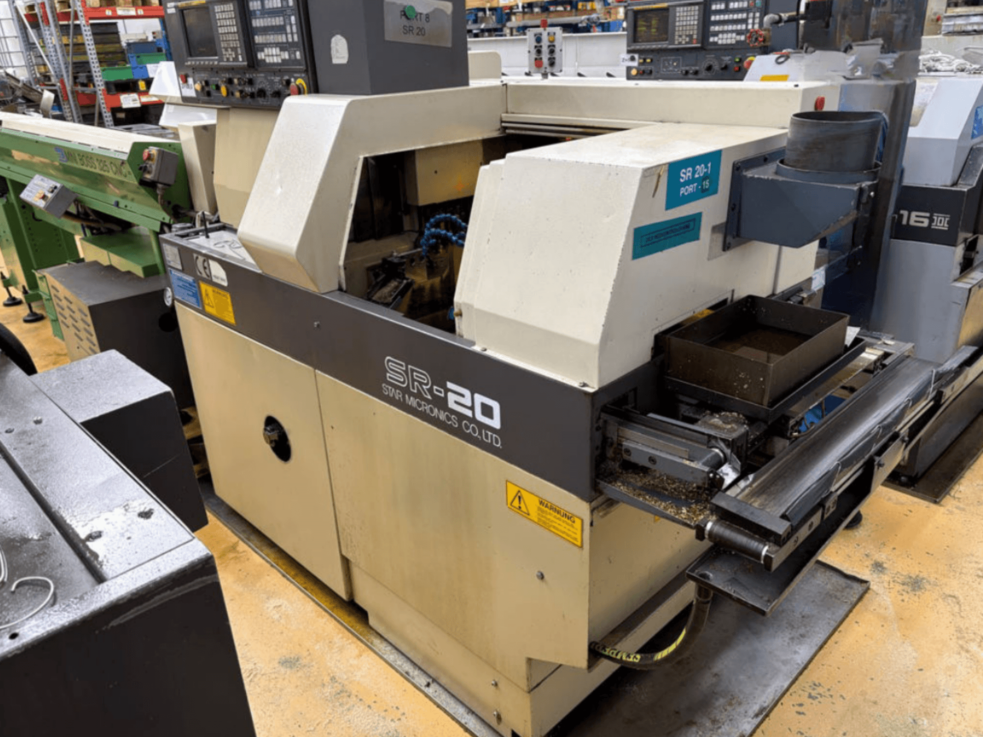 STAR MICRONICS SR20 İsviçre tipi torna tezgahının yandan görünümü; kontrol paneli ve talaşların bulunduğu takım alanı da görülmektedir.