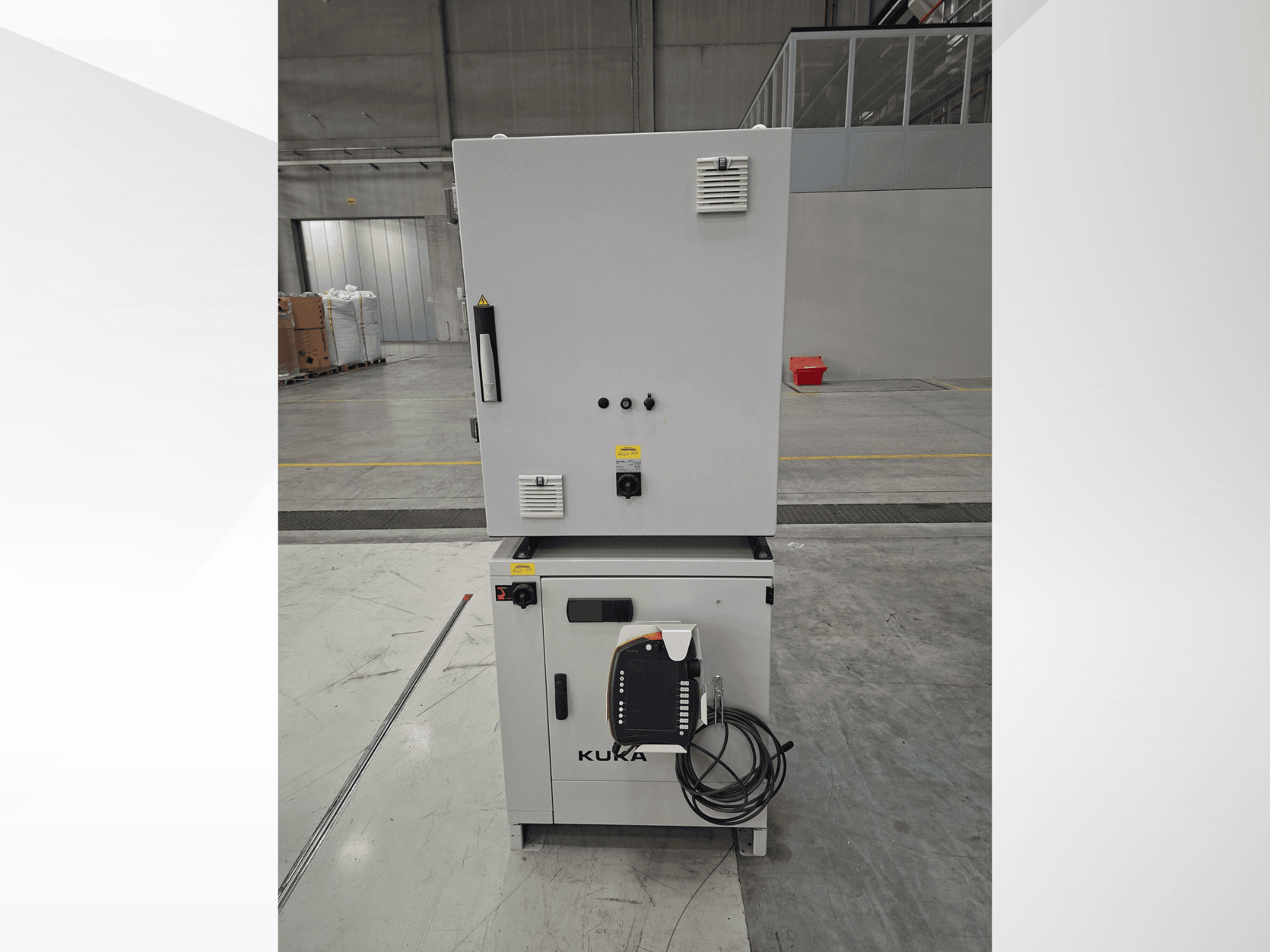 KUKA KR 90 R2700 PRO C4 FLR robot kolu kontrol ünitesi; geniş bir depo ortamında kontrol paneli ve güvenlik etiketlerini gösteren önden görünüm.