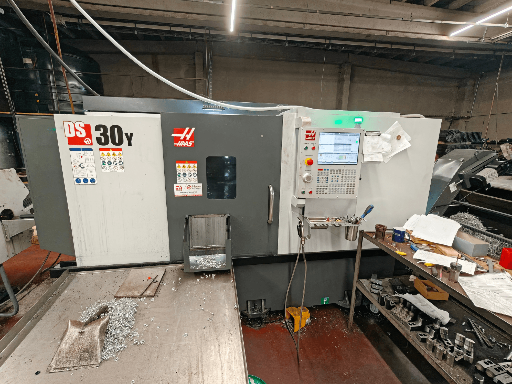 Bir atölyede bulunan HAAS DS30Y yatay torna tezgahı; kontrol paneli ve yüzeydeki metal talaşlarının görüldüğü önden görünüm.