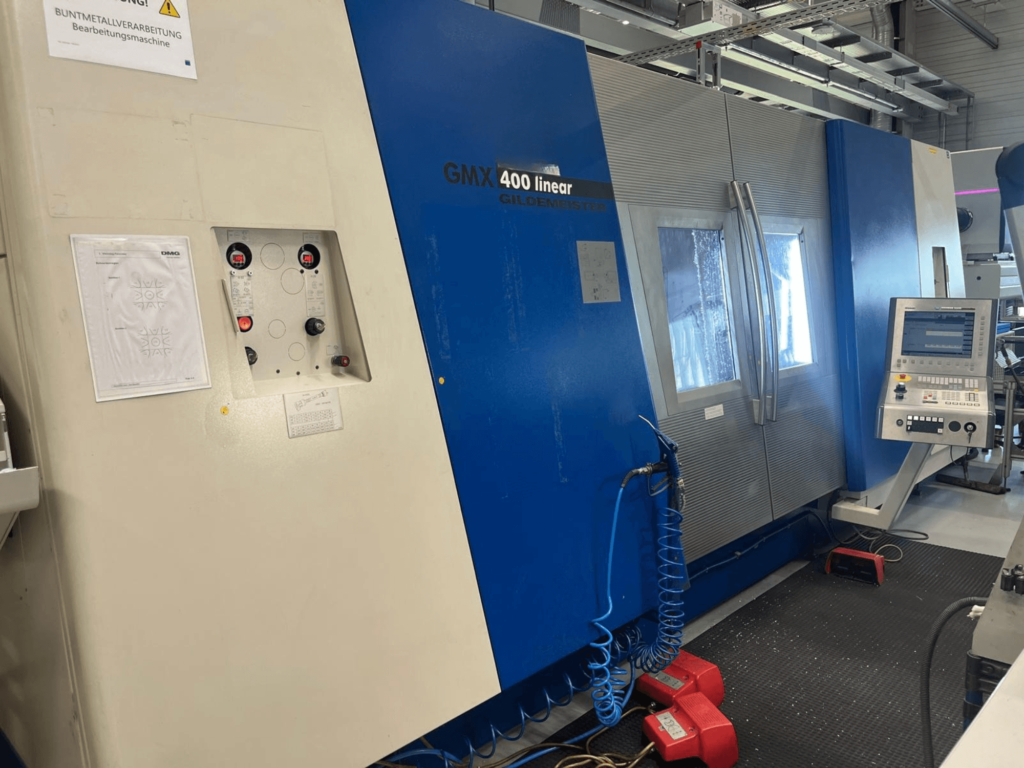 Gildemeister GMX 400 doğrusal torna-freze merkezi; kontrol paneli, soğutma sıvısı sistemi ve çalıştırma düğmelerini gösteren önden görünüm.