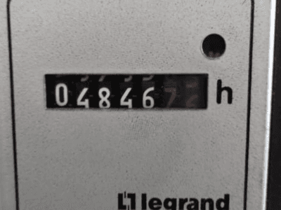 Legrand saat ölçer 048467.6, önden görünüm, kırmızı gösterge ışığı ve dokulu açık zemin üzerinde siyah rakamlar.