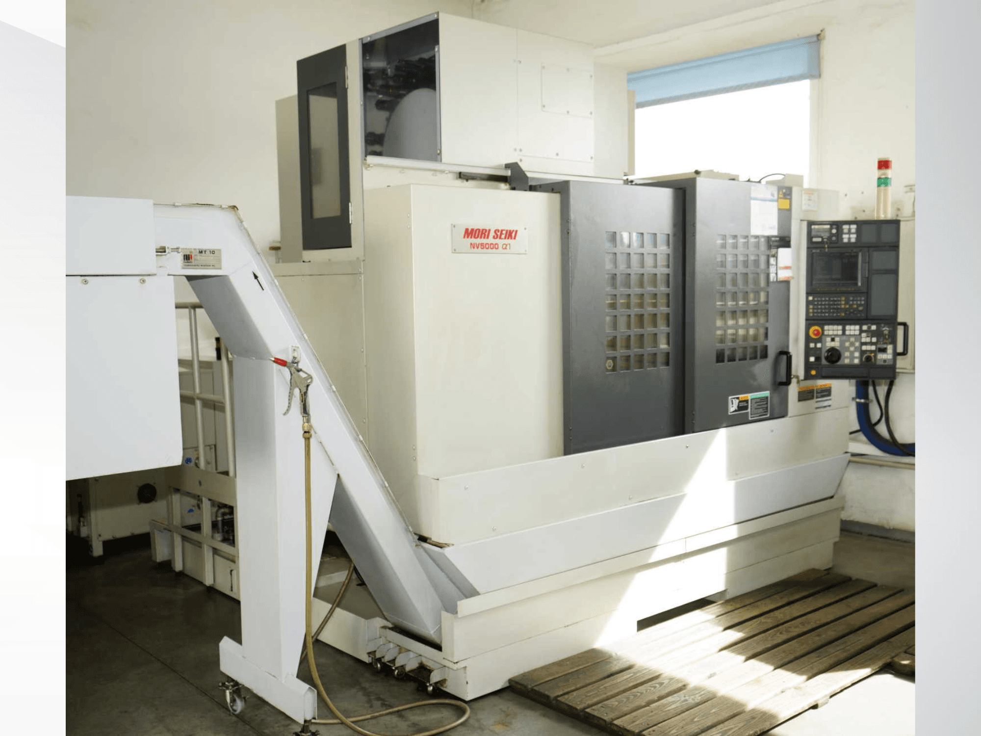 MORI SEIKI NV 5000 alpha1 dikey işleme merkezinin önden görünümü; kontrol paneli, güvenlik özellikleri ve yükleme alanı gösterilmektedir.