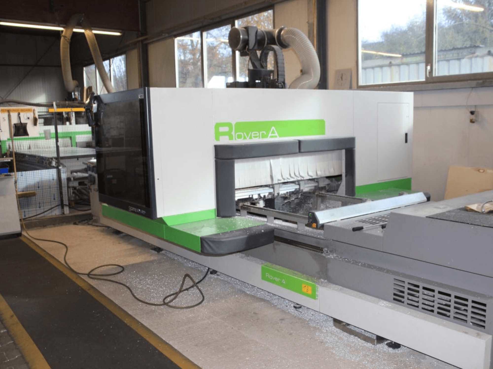 BIESSE Rover A 1232 CNC router, endüstriyel bir ortamda kesim alanını ve kontrol panelini gösteren yandan görünüm.