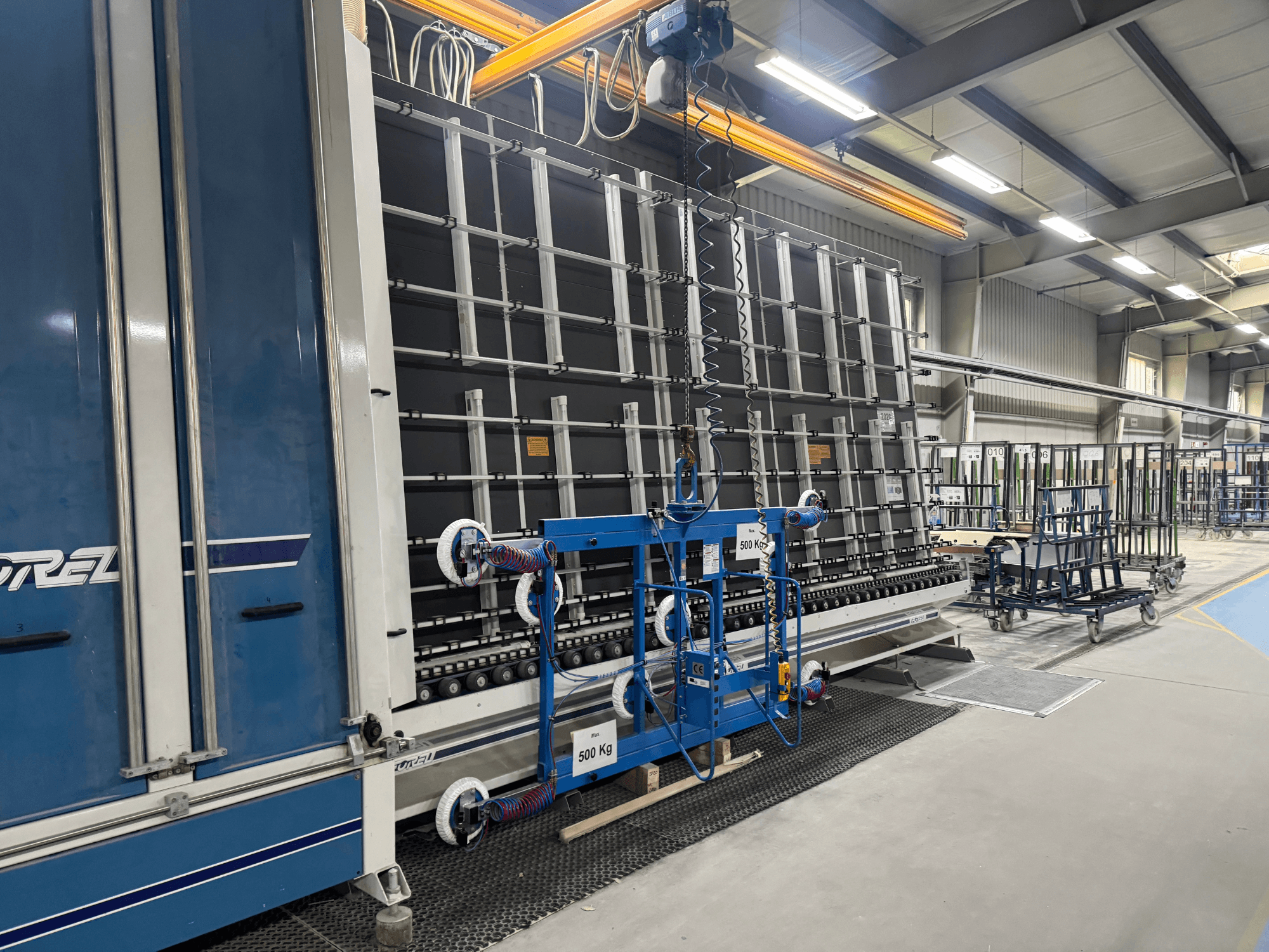 Drel'in büyük bir çerçeve ve kaldırma mekanizmasına sahip endüstriyel ekipmanı, bir fabrika ortamında yandan gösterilmiştir.